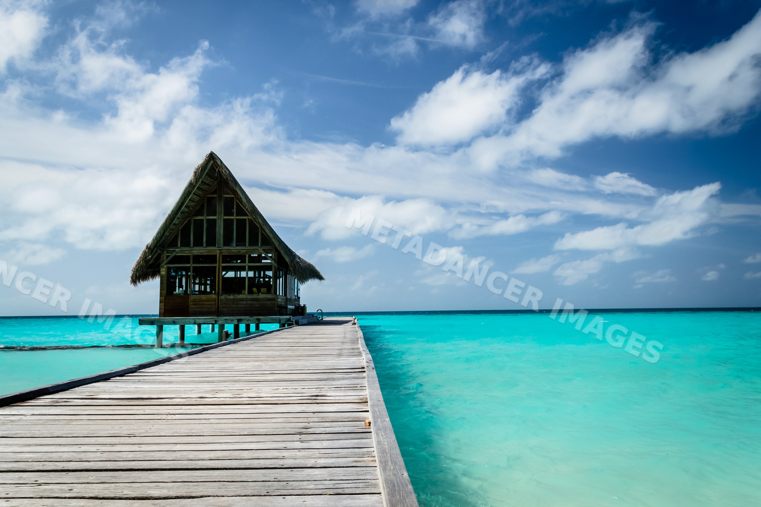 Wooden pier with thatched hut over turquoise water