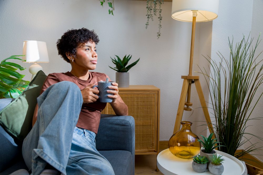 African American woman relaxing on couch with cup in cozy living room