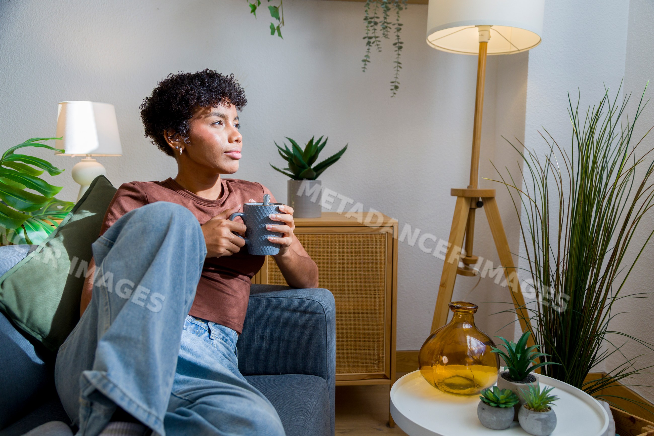 African American woman relaxing on couch with cup in cozy living room
