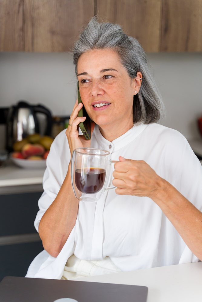 Middle aged white woman drinking coffee and talking on phone