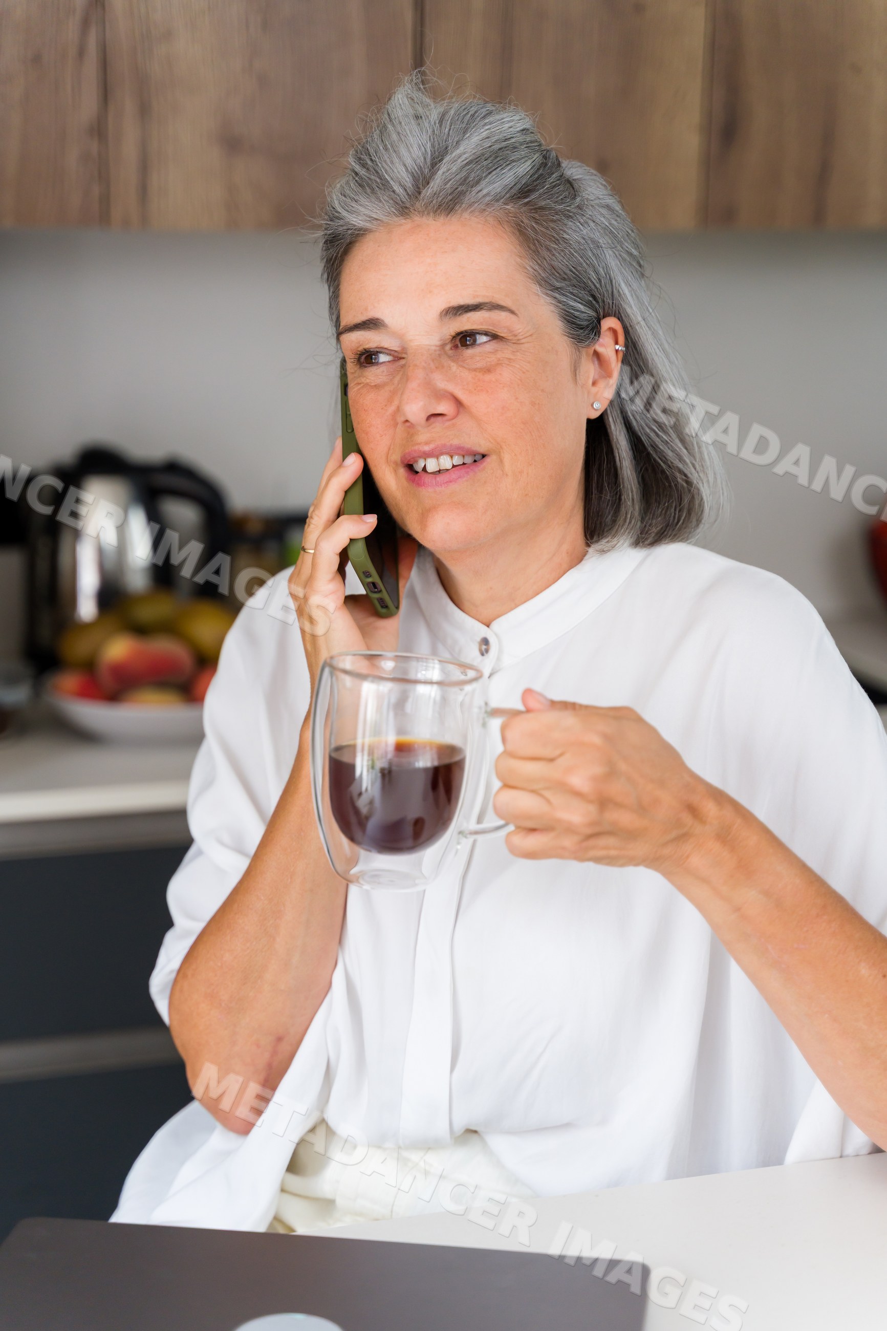 Middle aged white woman drinking coffee and talking on phone