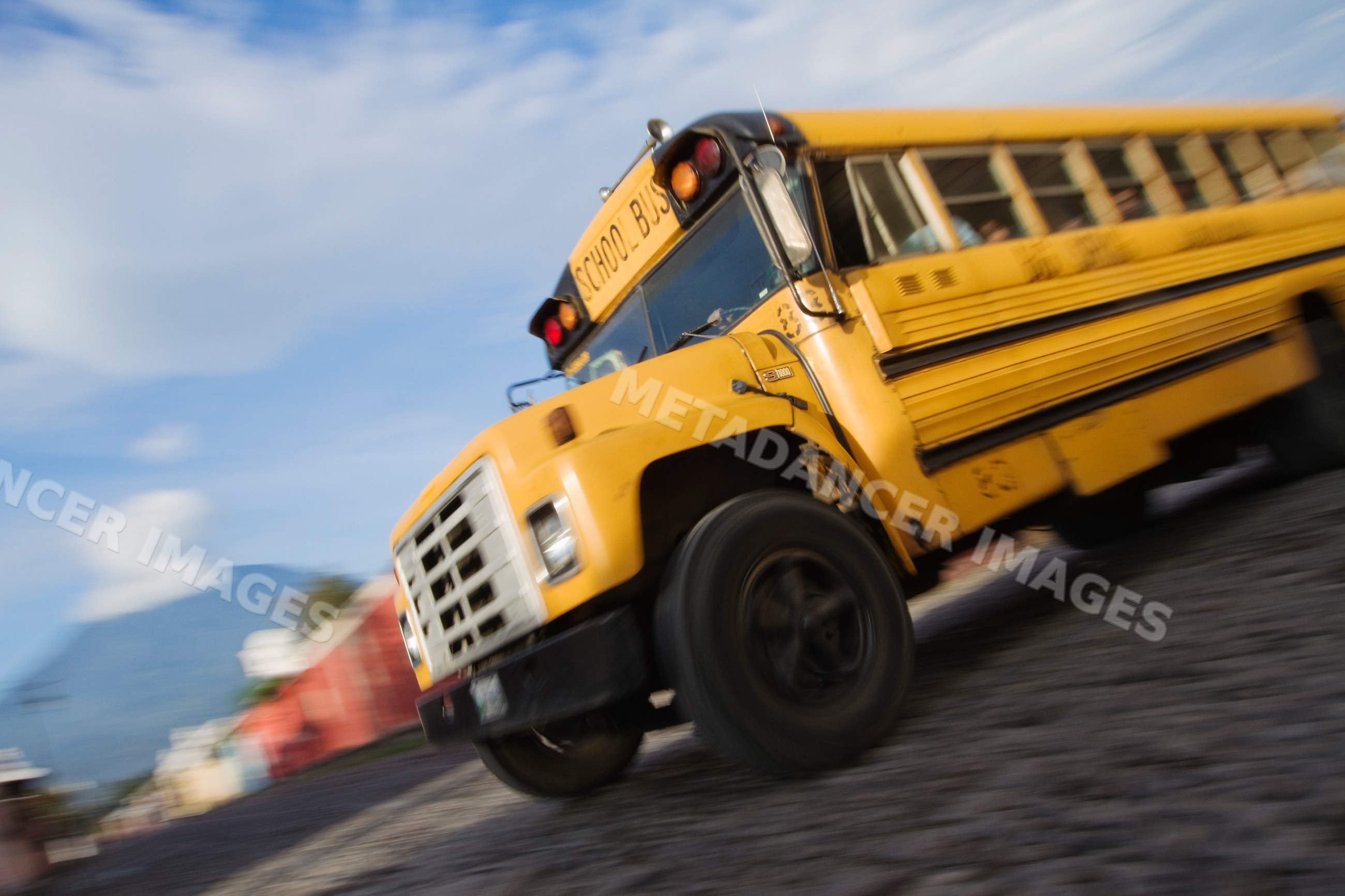 Yellow school bus moving on cobblestone street guatemala