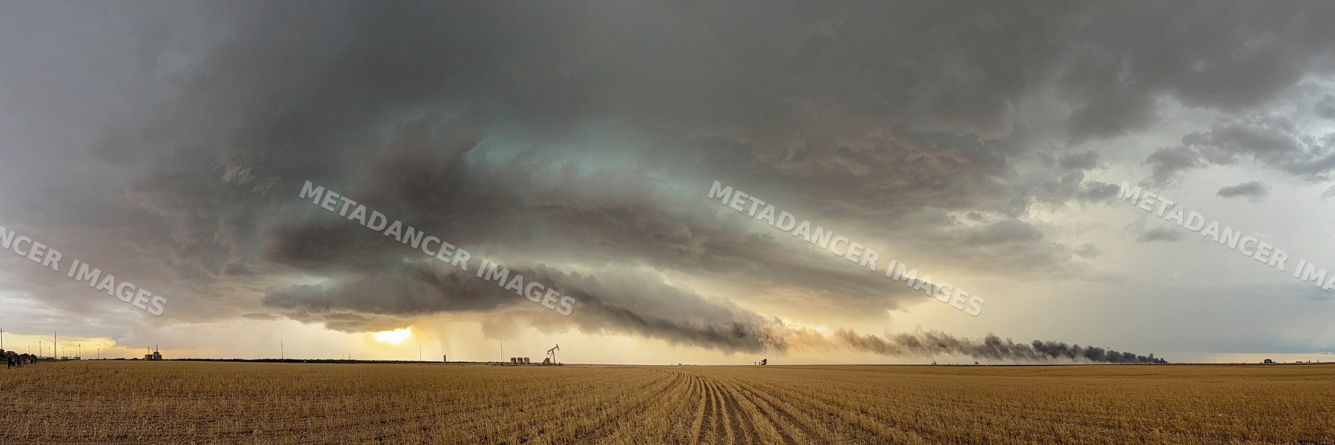 Supercell storm cloud with smoke plume over rural field