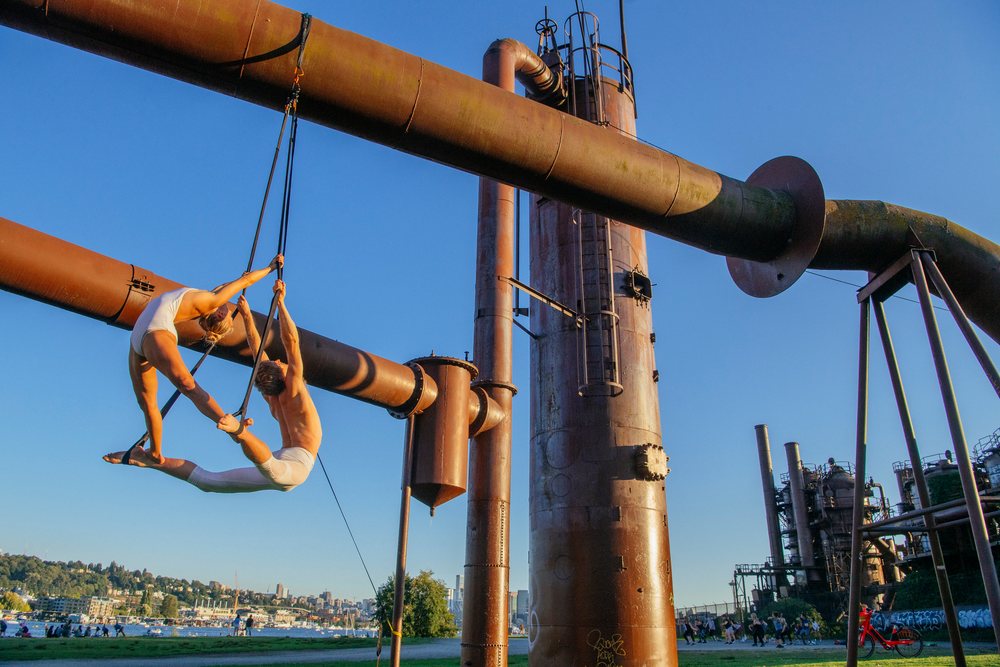 Aerial silk acrobats perform on industrial pipes