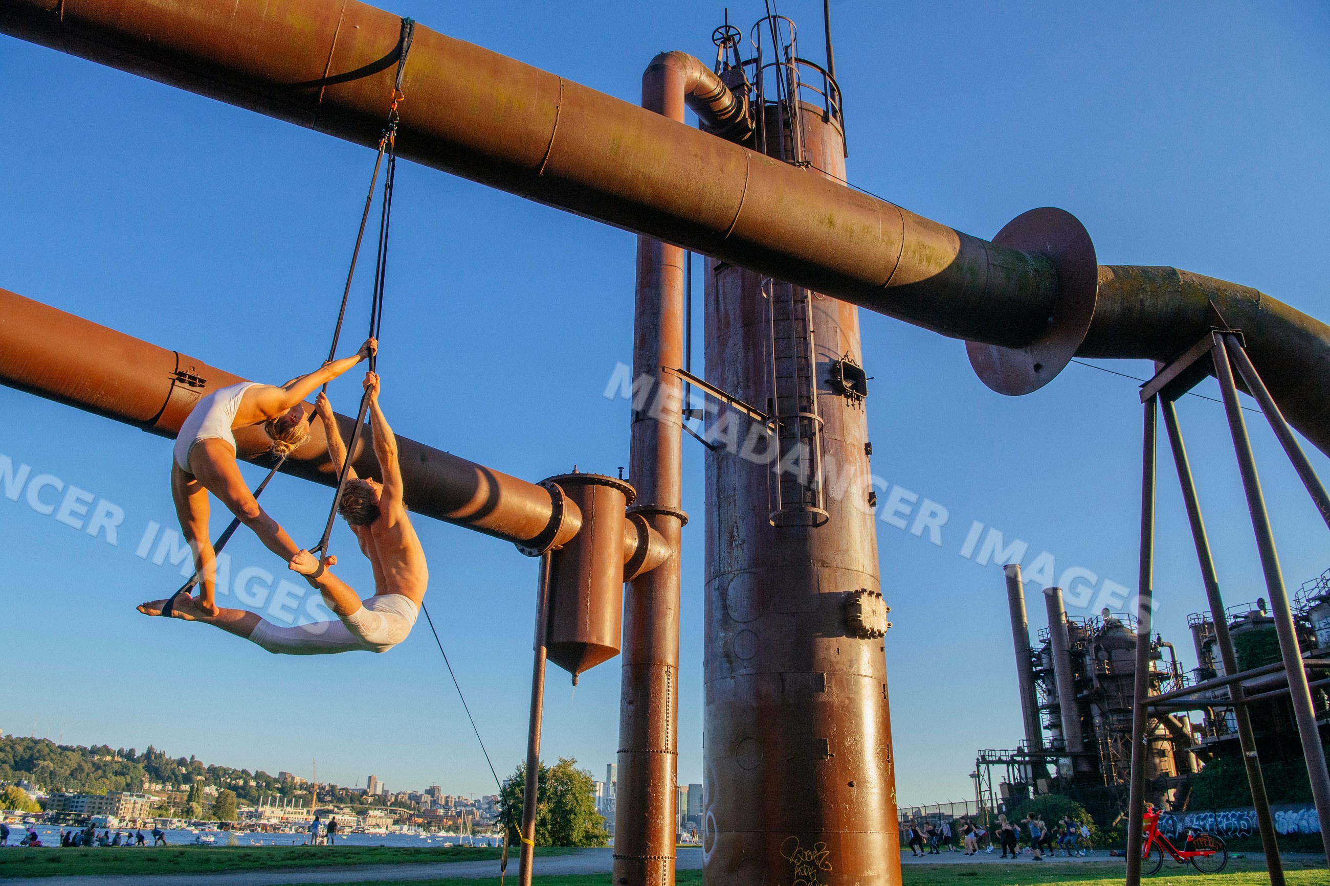 Aerial silk acrobats perform on industrial pipes