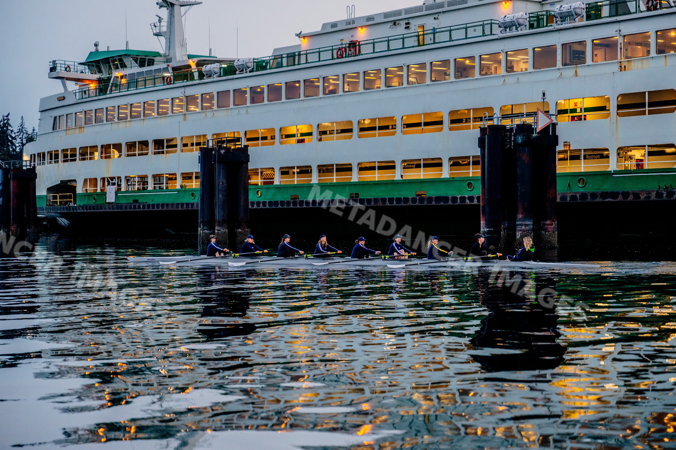 A rowing team practicing on calm water near a ferry dock in wa USA