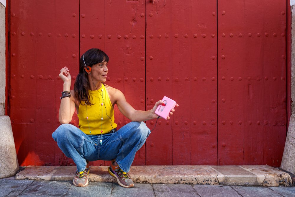 Hispanic woman listening to music on cassette player squatting by red