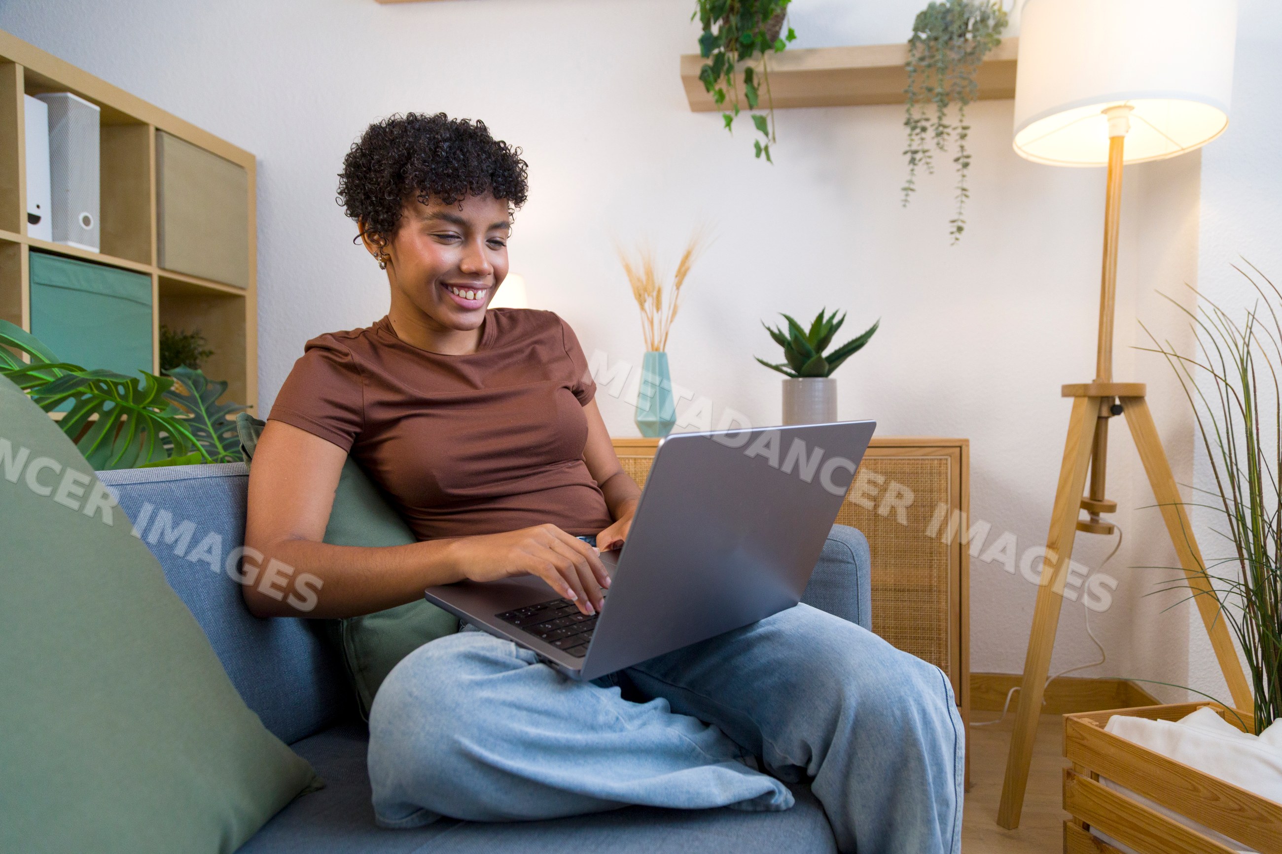 Young African American woman working on a laptop at home on a sofa