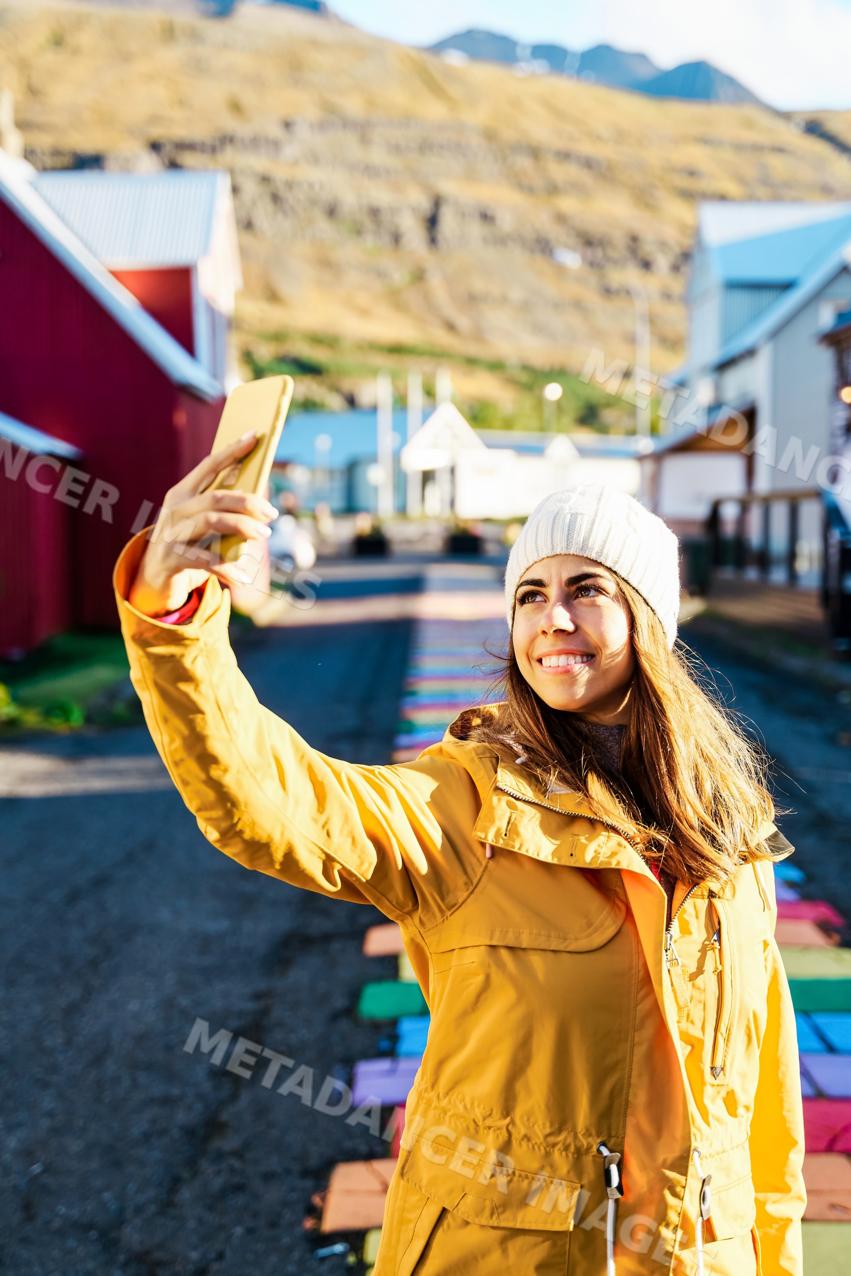 A young white woman takes a selfie on a colorful street