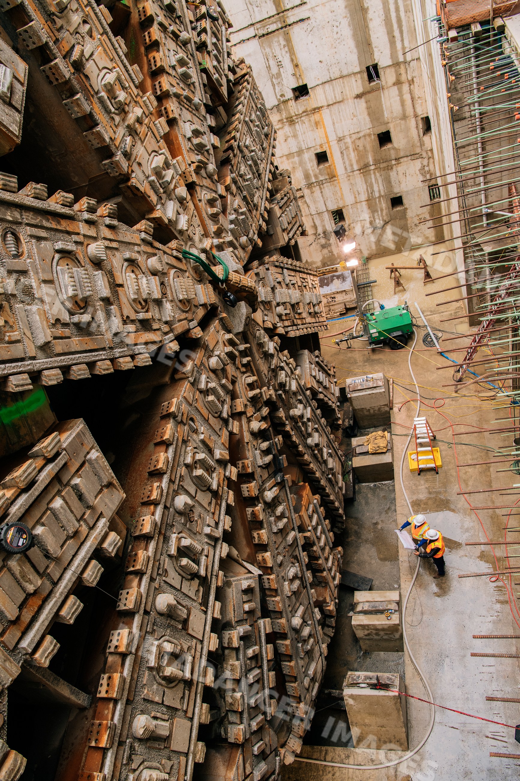 Two white workers review plans by a tunnel boring machine