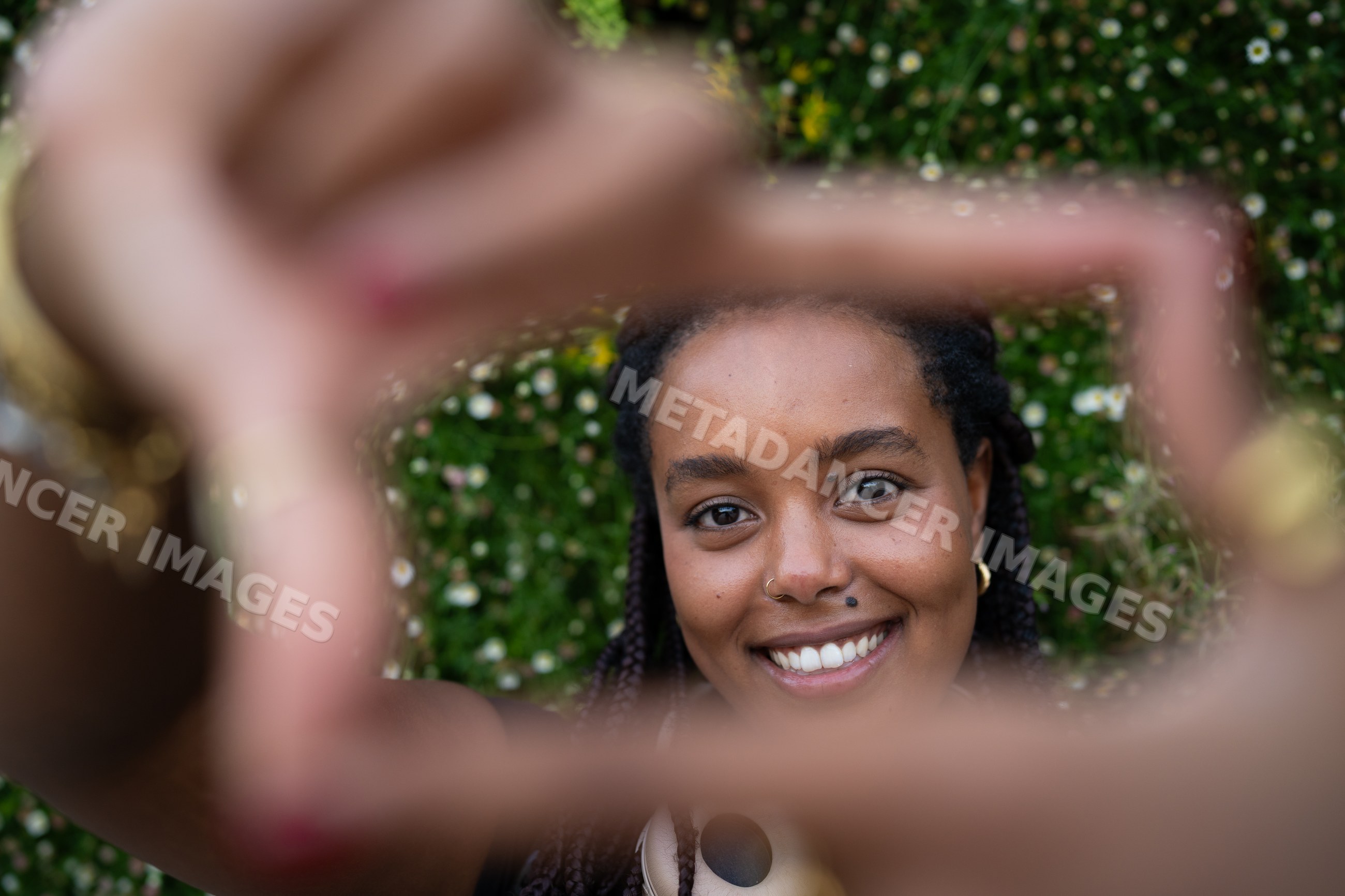 A smiling African American woman framing her face with hands