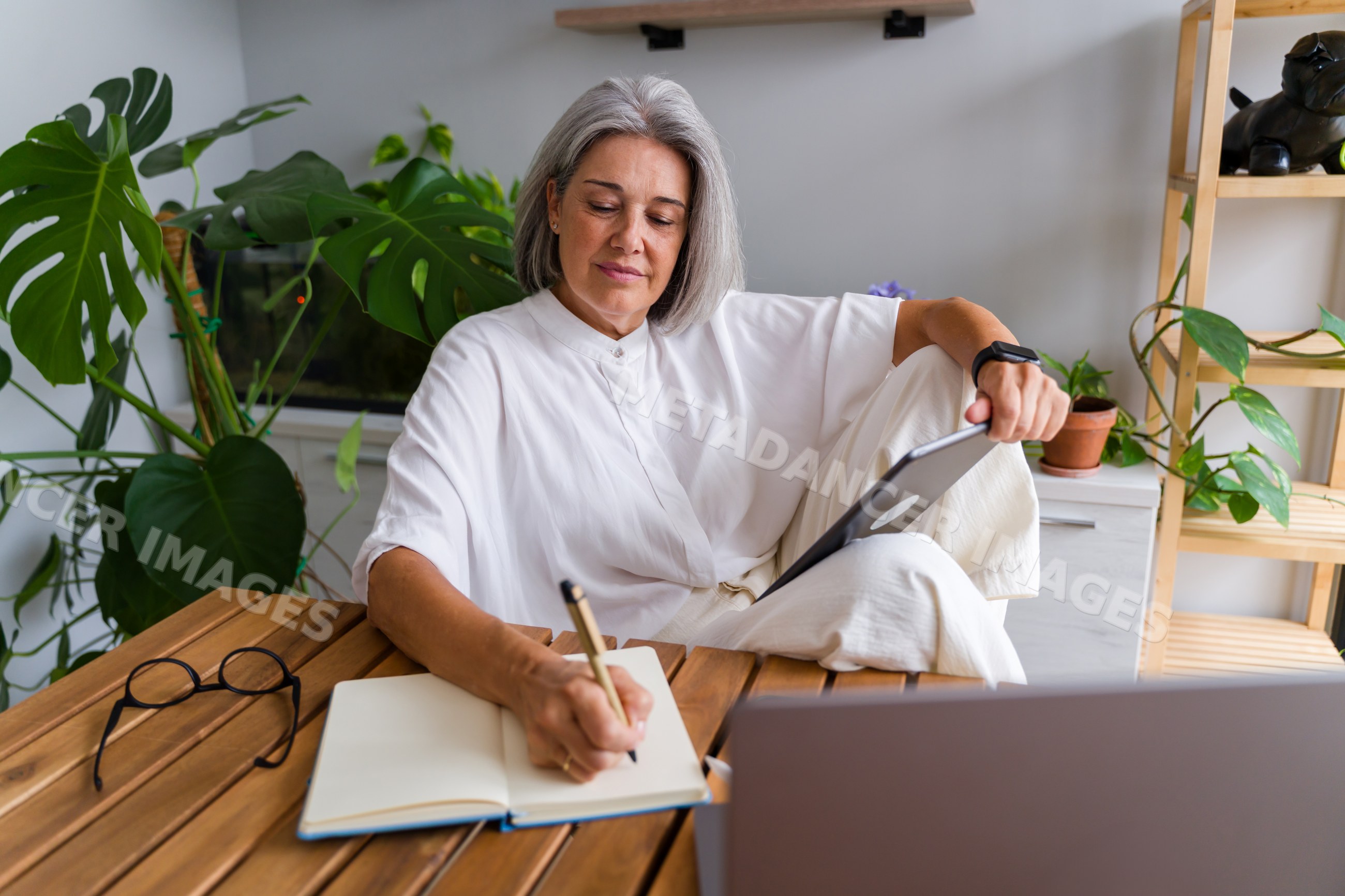 White Woman taking notes while holding a tablet