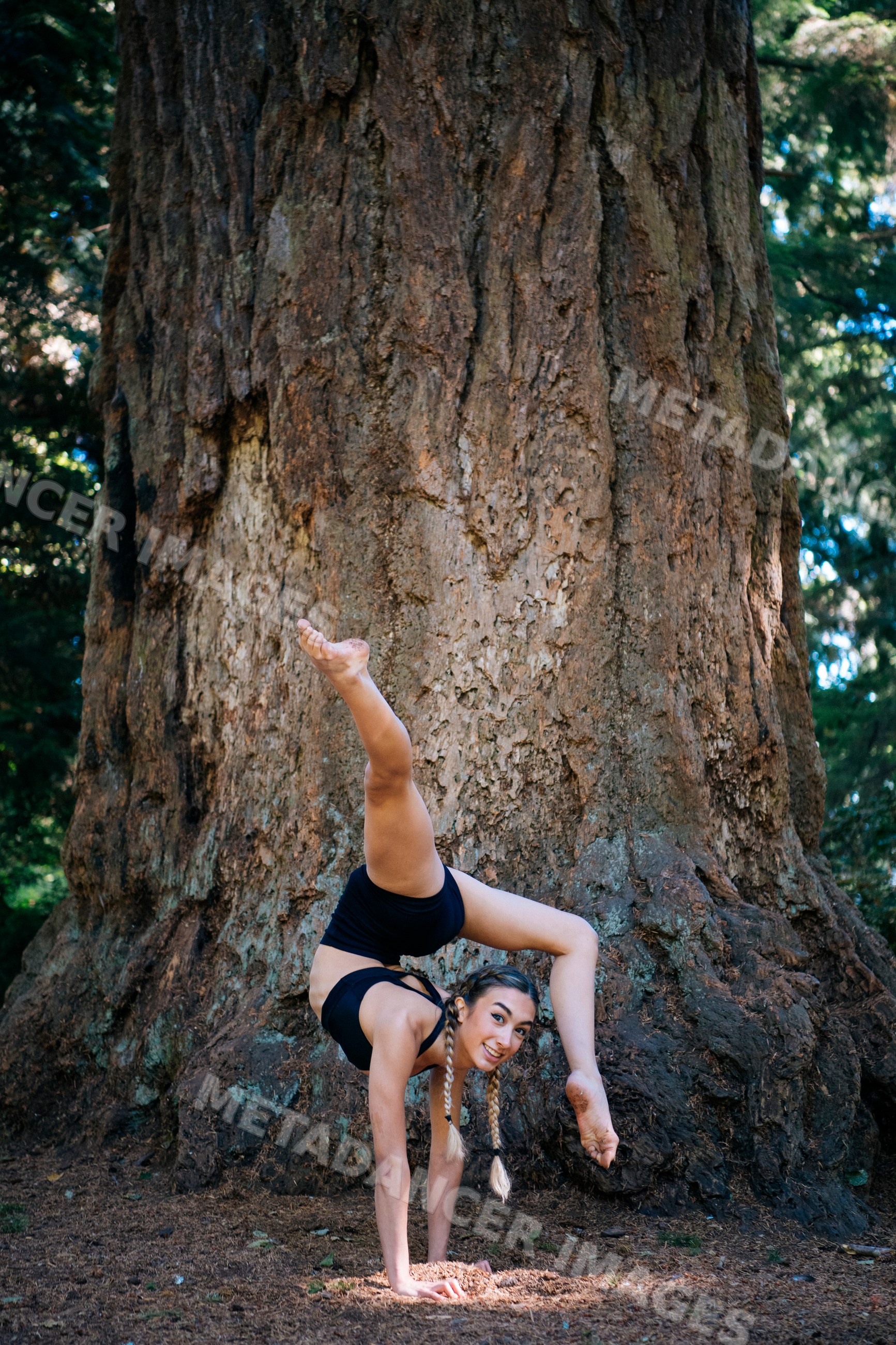 Contortionist performing handstand pose outdoors in forest