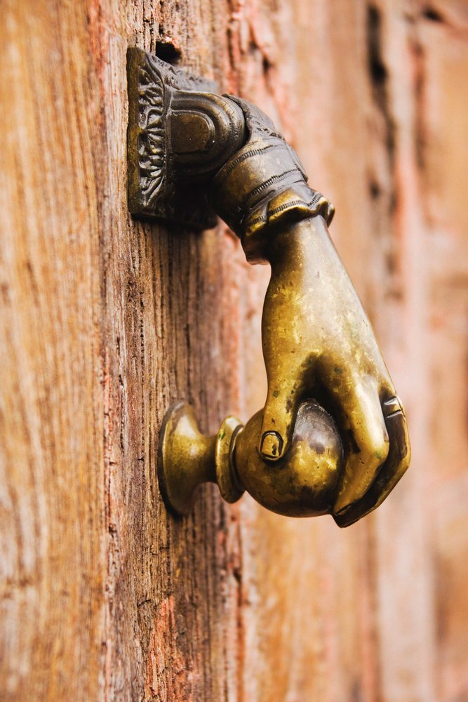 Close-up of bronze hand-shaped door knocker on wooden door