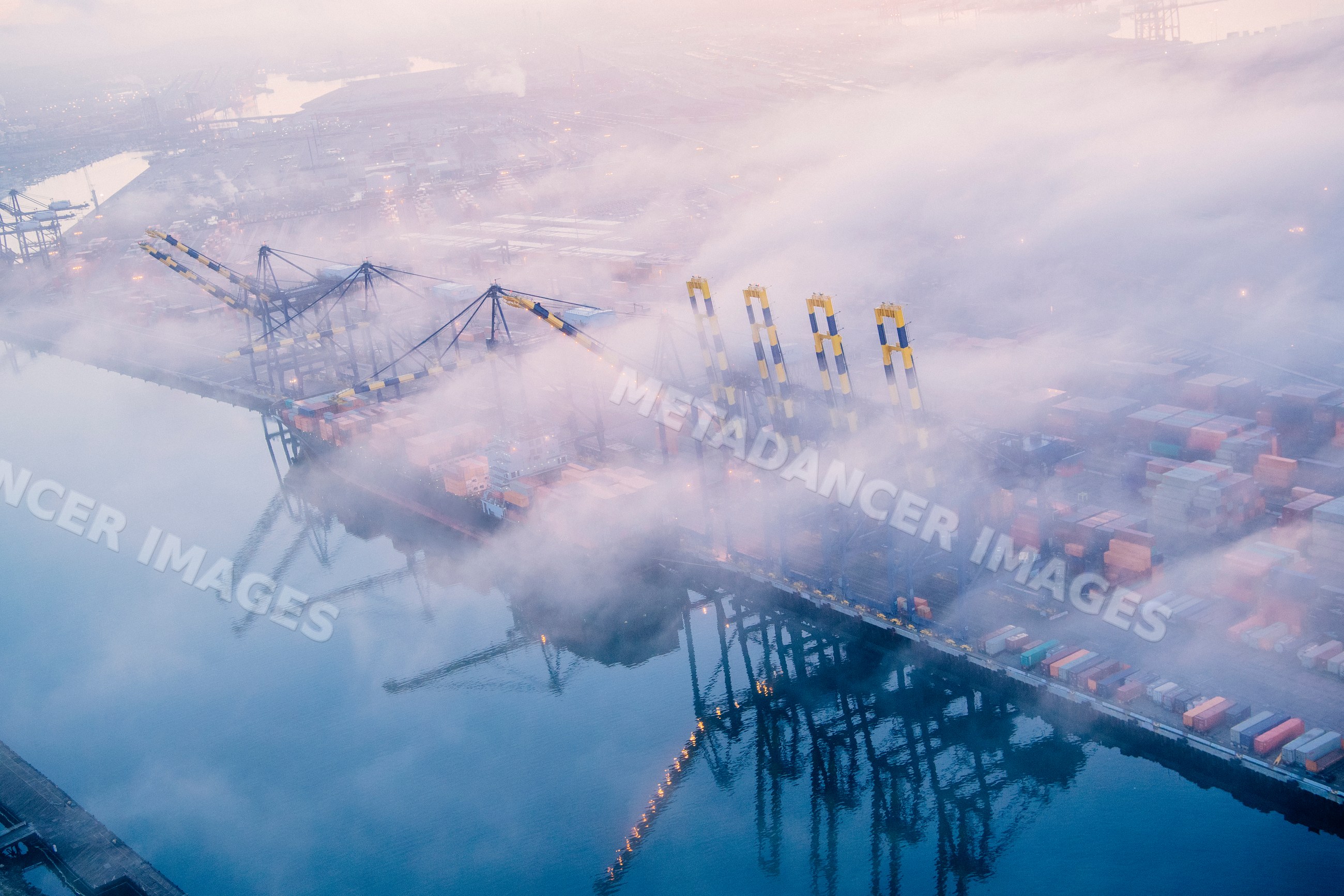 Container terminal with cargo cranes on foggy morning in a beach