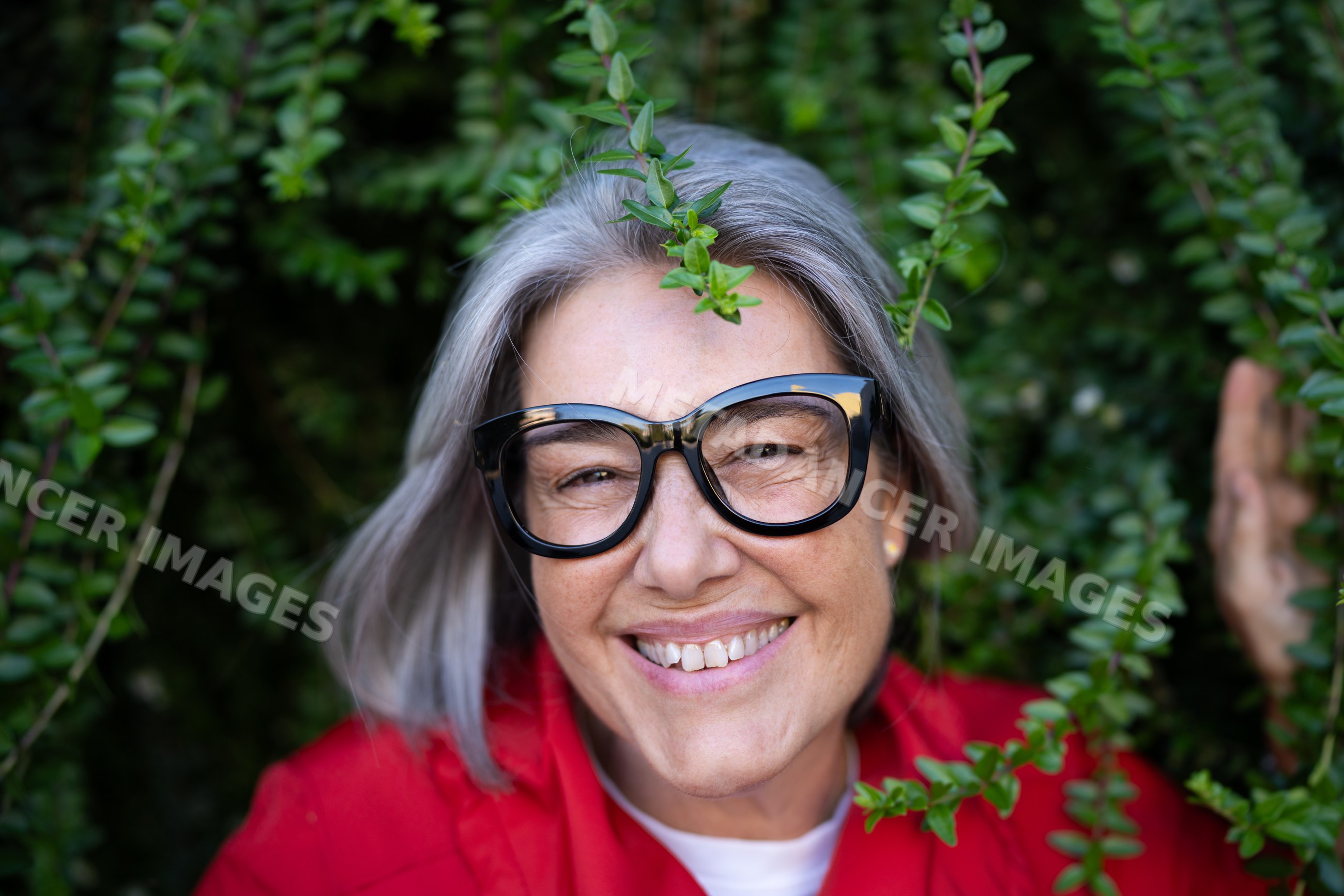 Smiling mature white woman with gray hair and black glasses outdoors