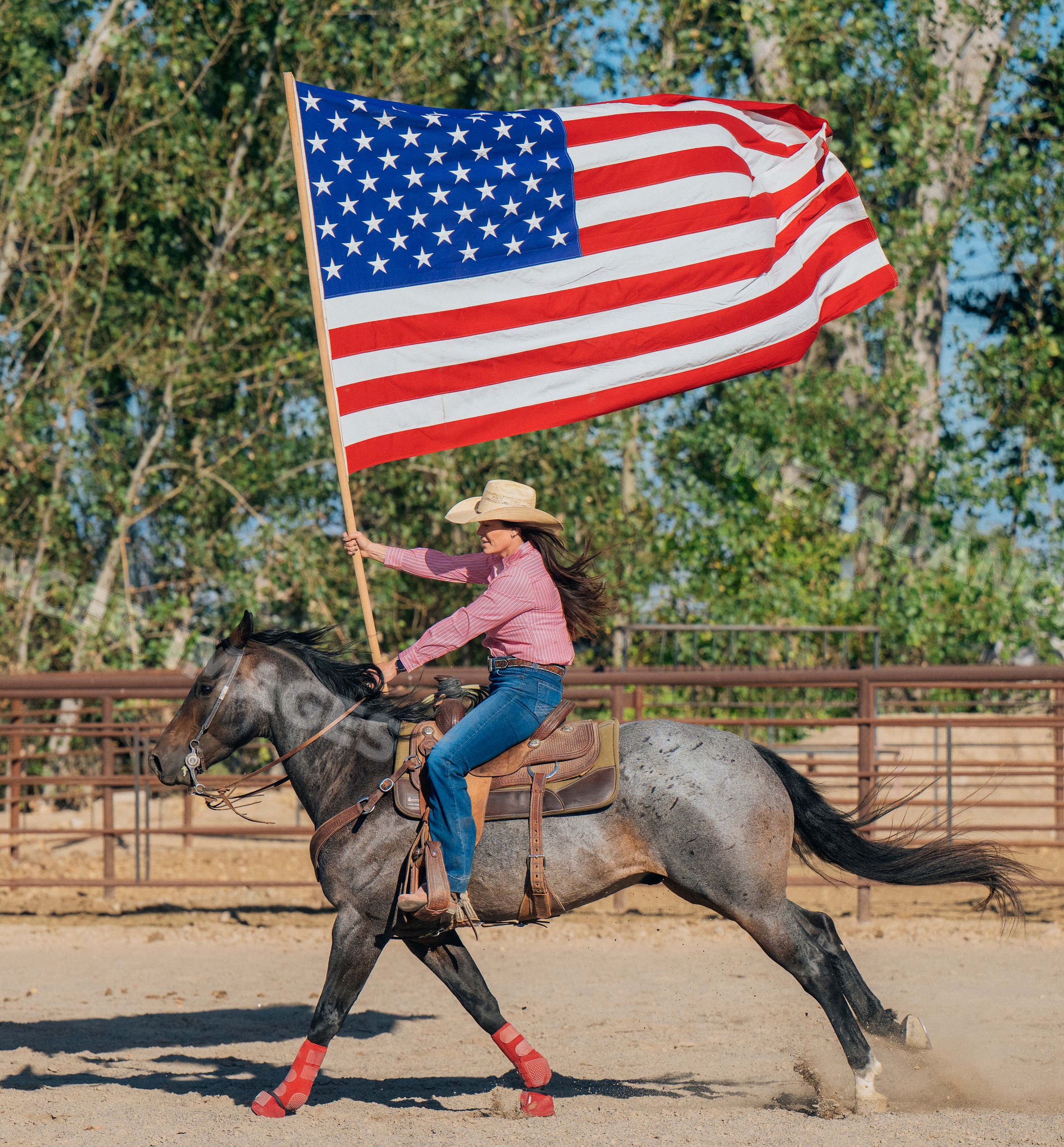 White woman riding horse carrying american flag