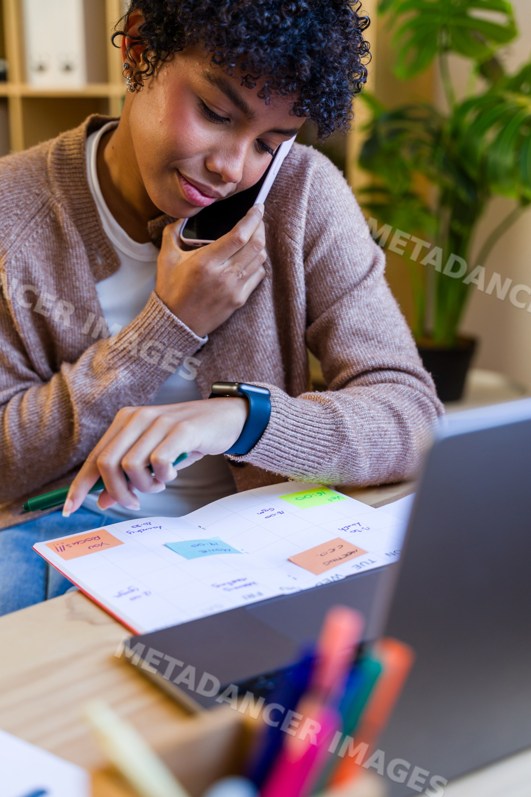 African American woman making a phone call and checking calendar