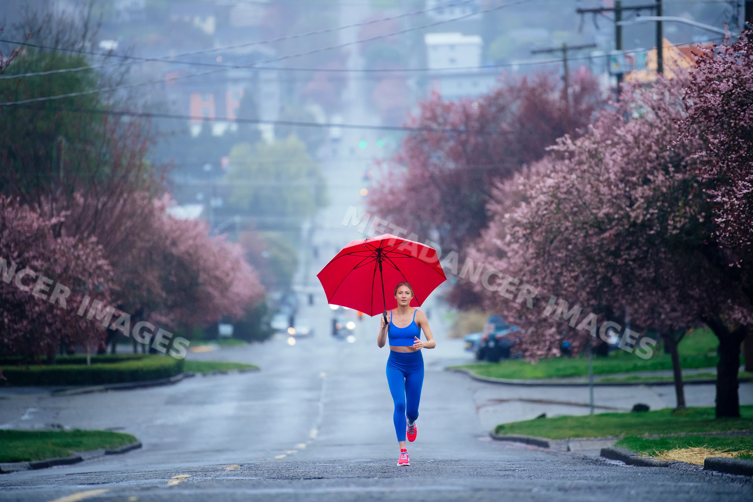 White woman running with red umbrella on rainy street with cherry