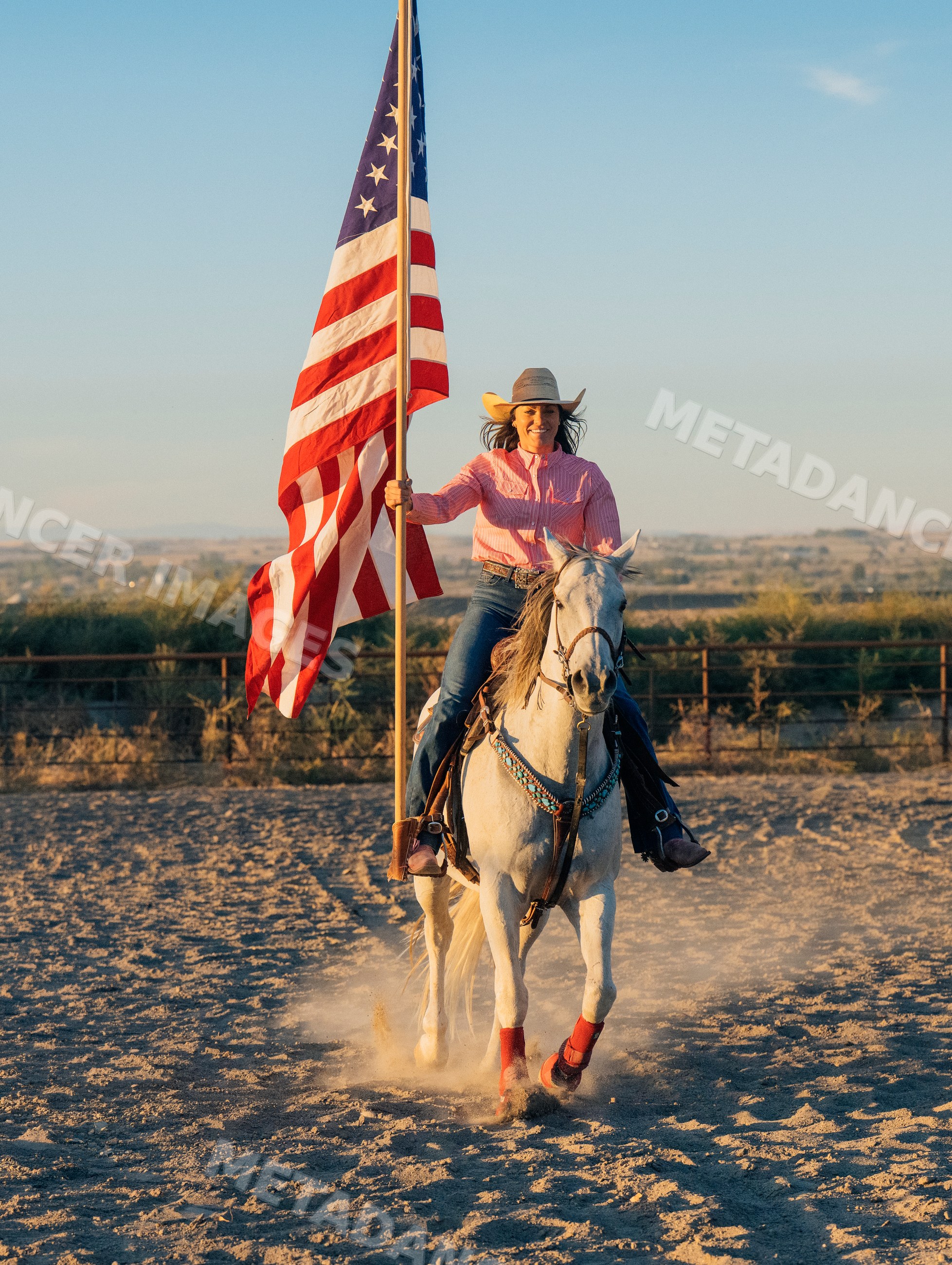 Woman riding white horse holding american flag outdoors