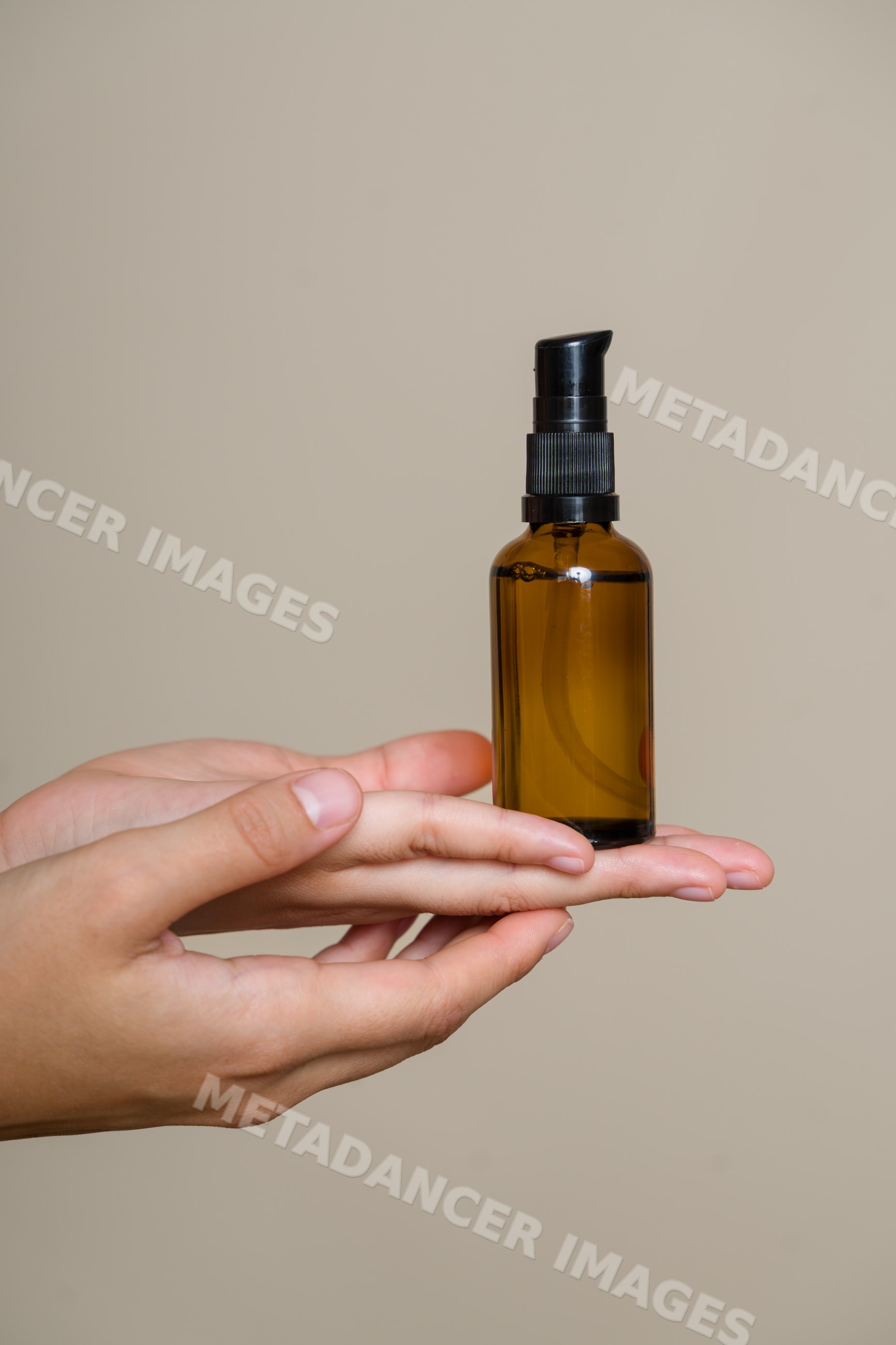 Hand holding amber glass pump dispenser bottle