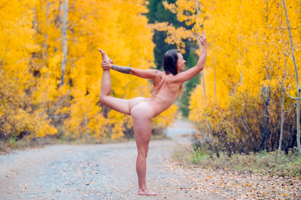 Nude white woman in yoga pose on forest path with fall colors
