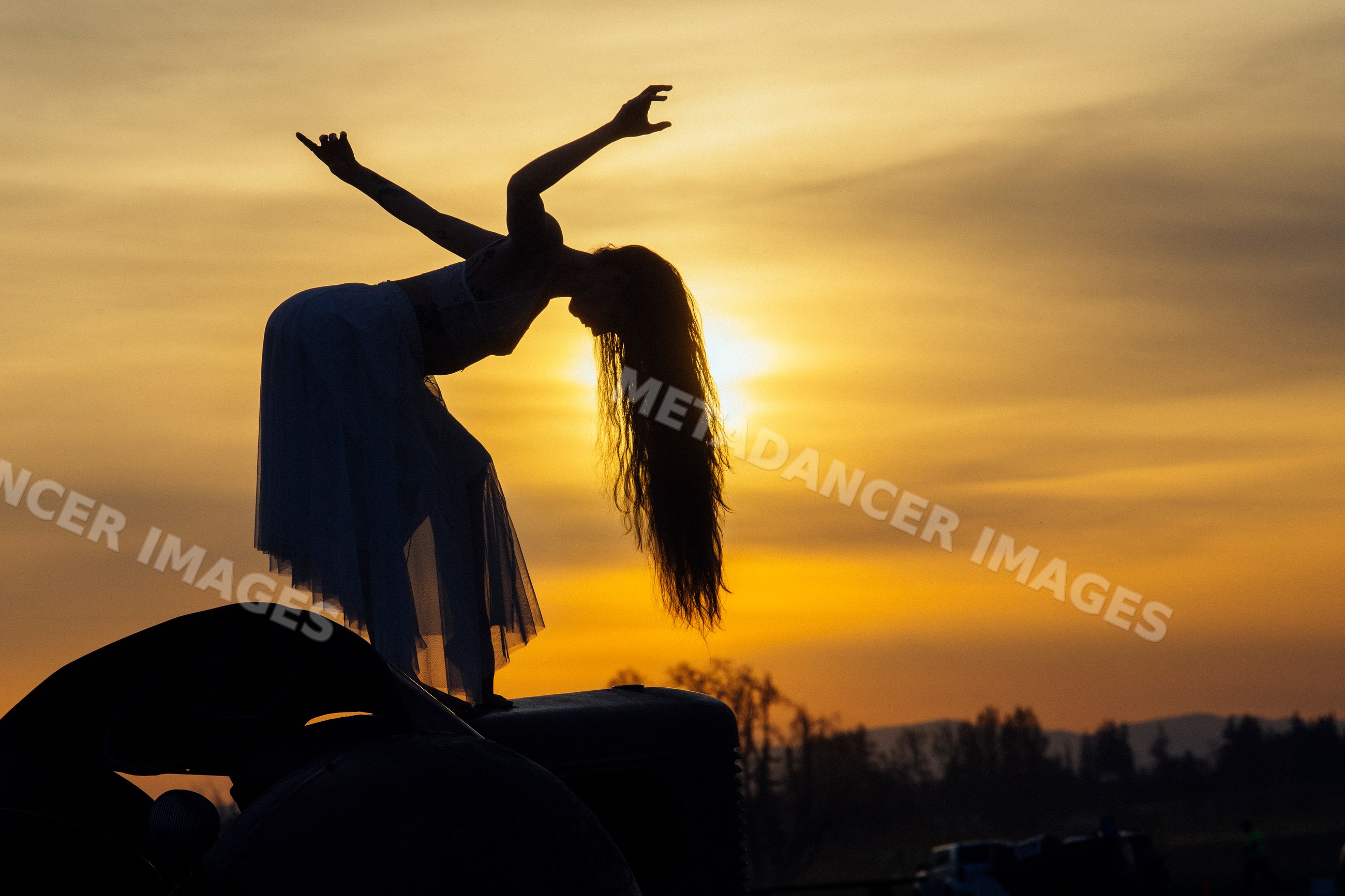 White woman dancing in silhouette at sunset outdoors