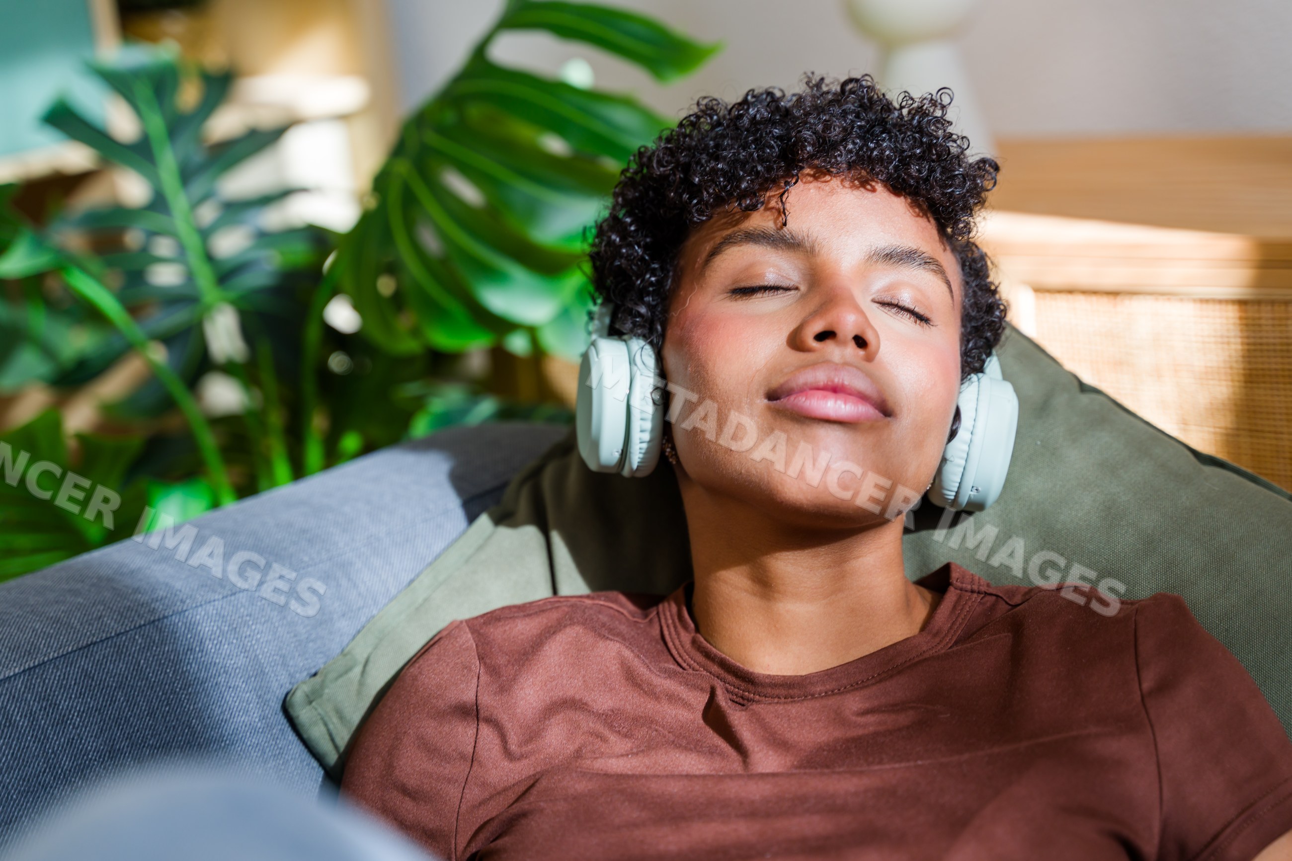 African American woman relaxing on couch with headphones and indoor