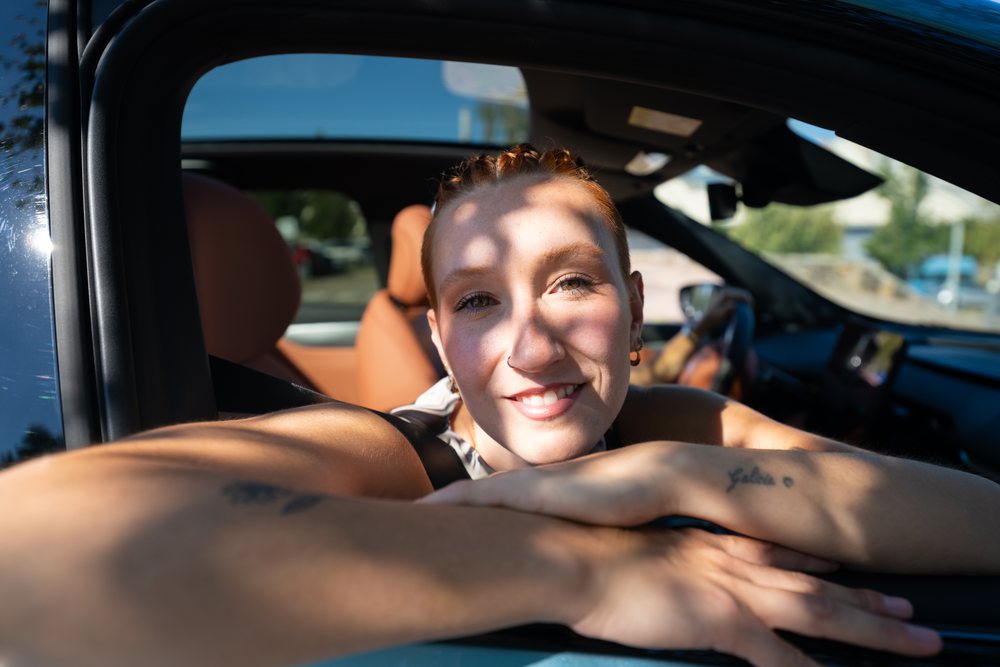 White woman smiling through car window outdoors