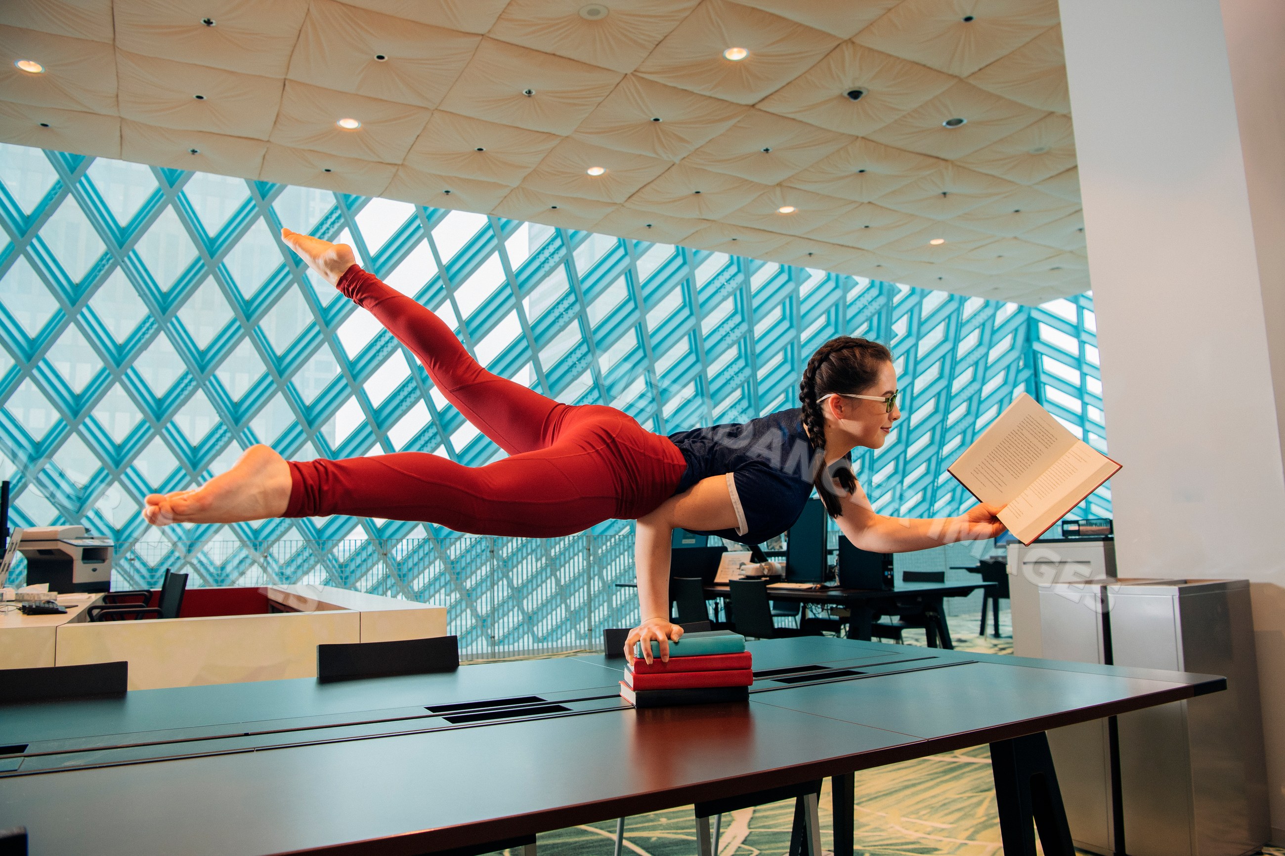 Woman reading book while balancing on one arm