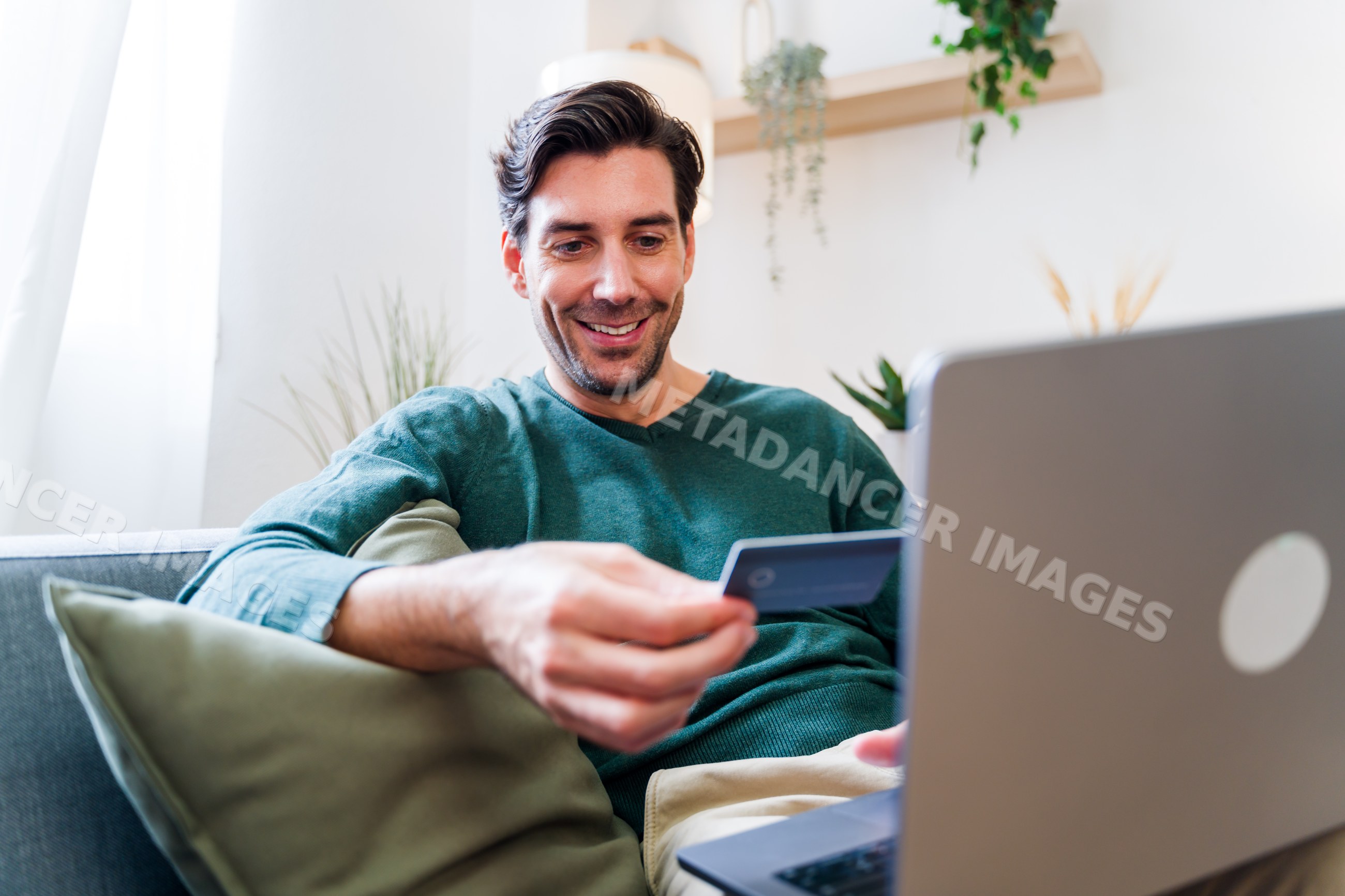 White man shopping online with credit card on laptop at home
