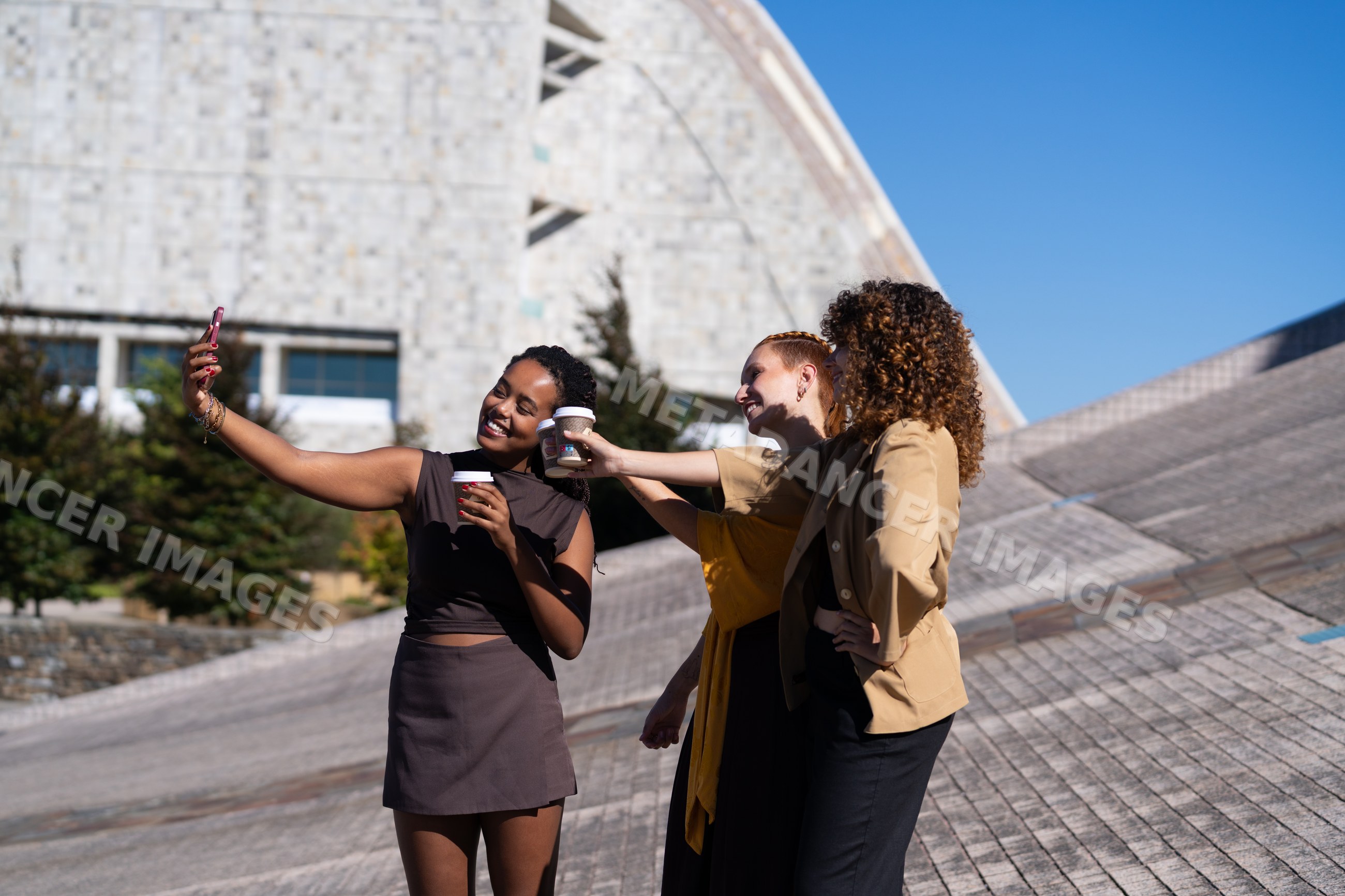 African American and white women taking selfie with coffee cups