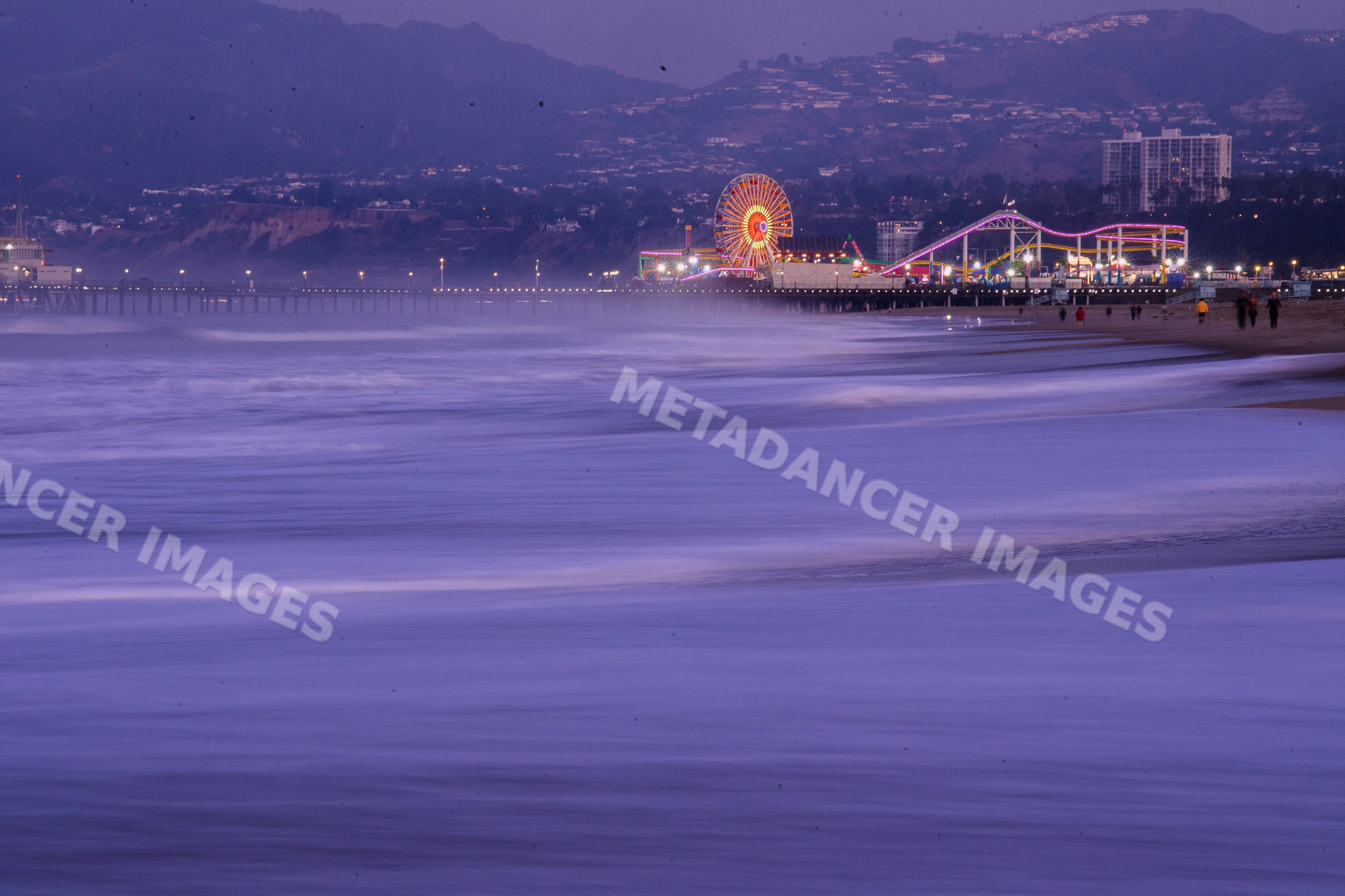 Santa Monica pier at dusk with ocean waves on the beach