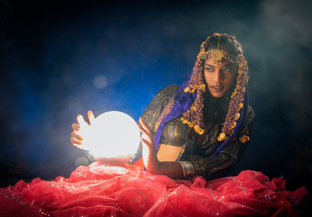 A South Asian woman fortune teller holding a glowing crystal ball