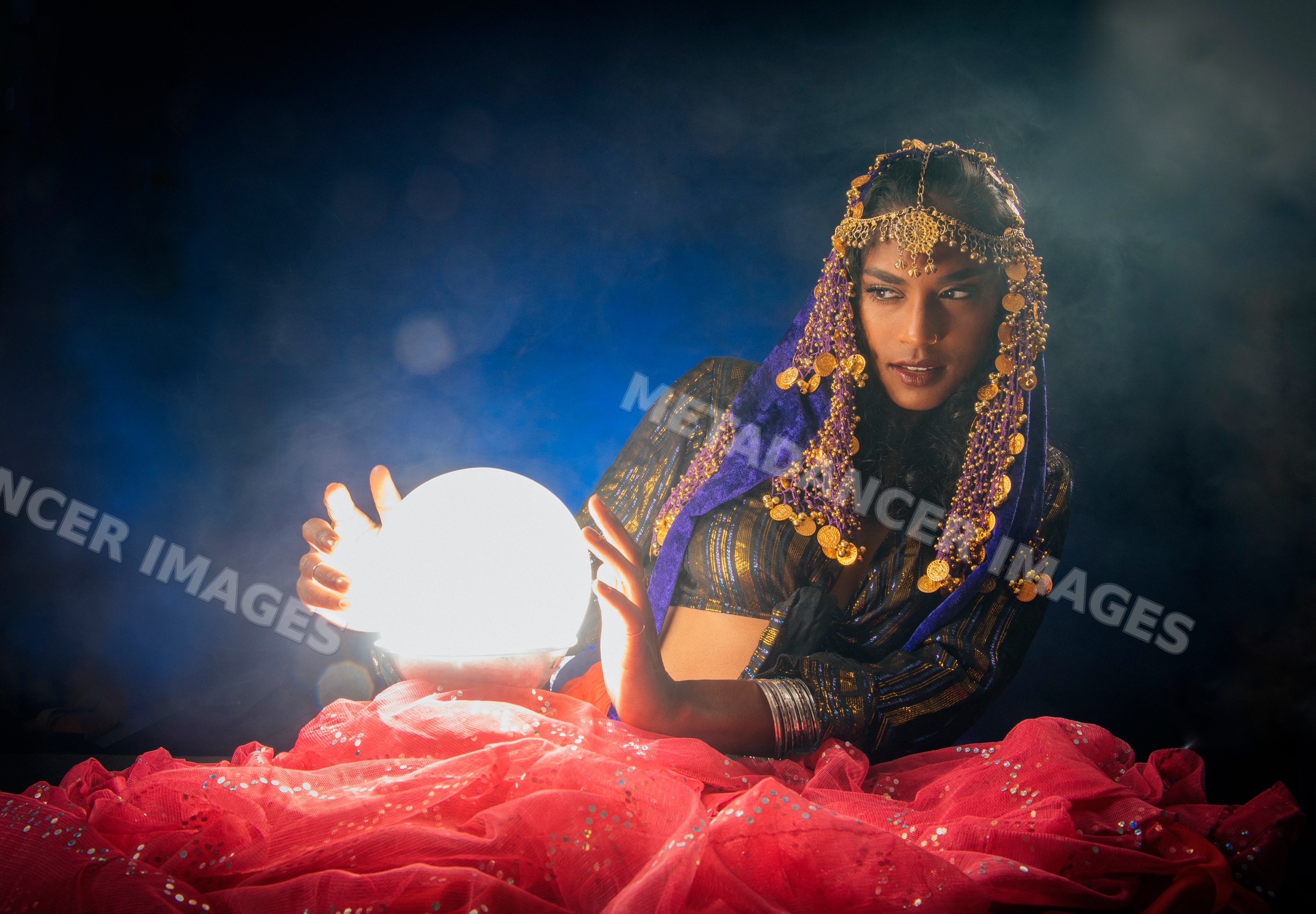 A South Asian woman fortune teller holding a glowing crystal ball