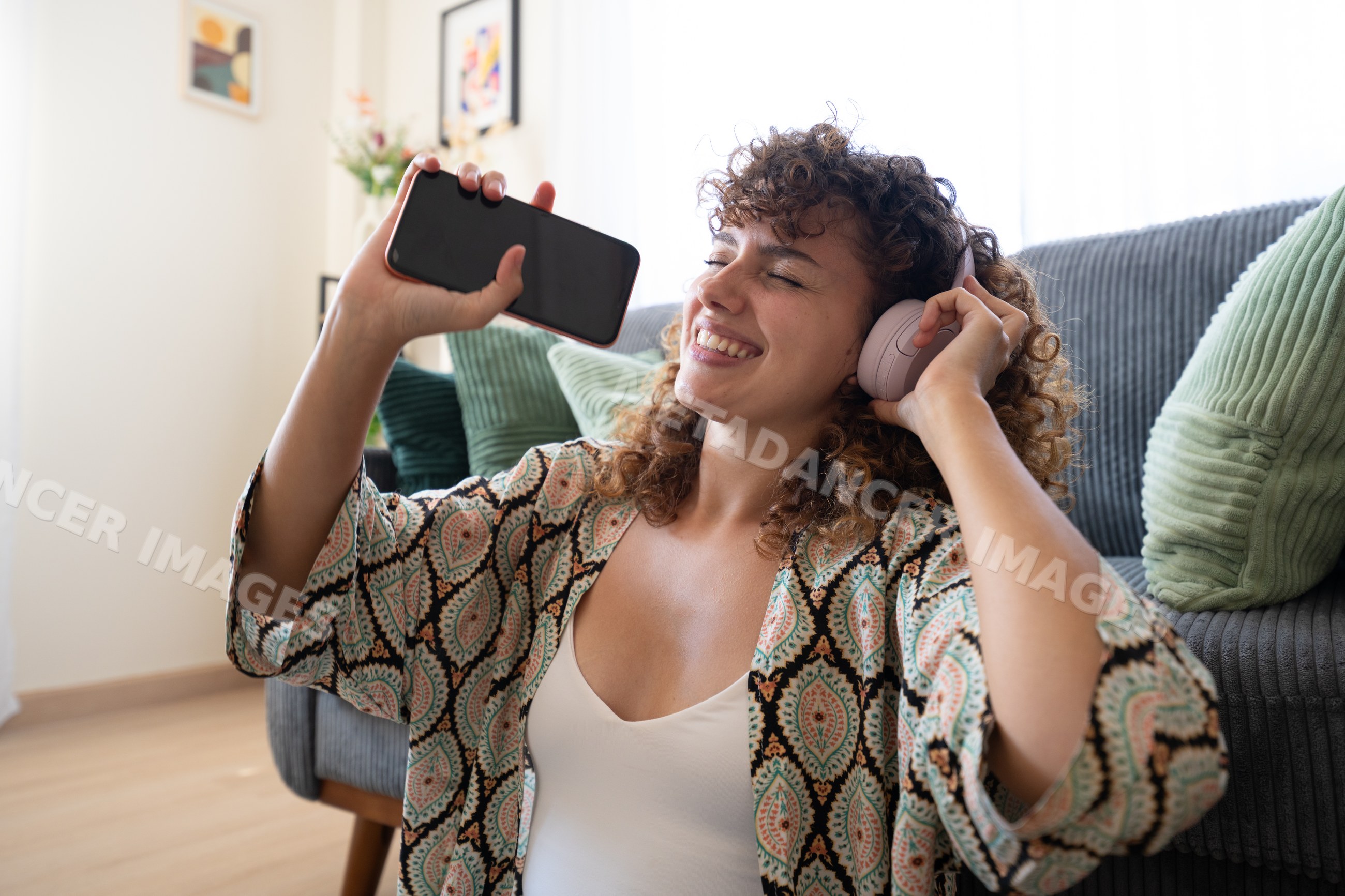 White woman listening to music on headphones holding smartphone