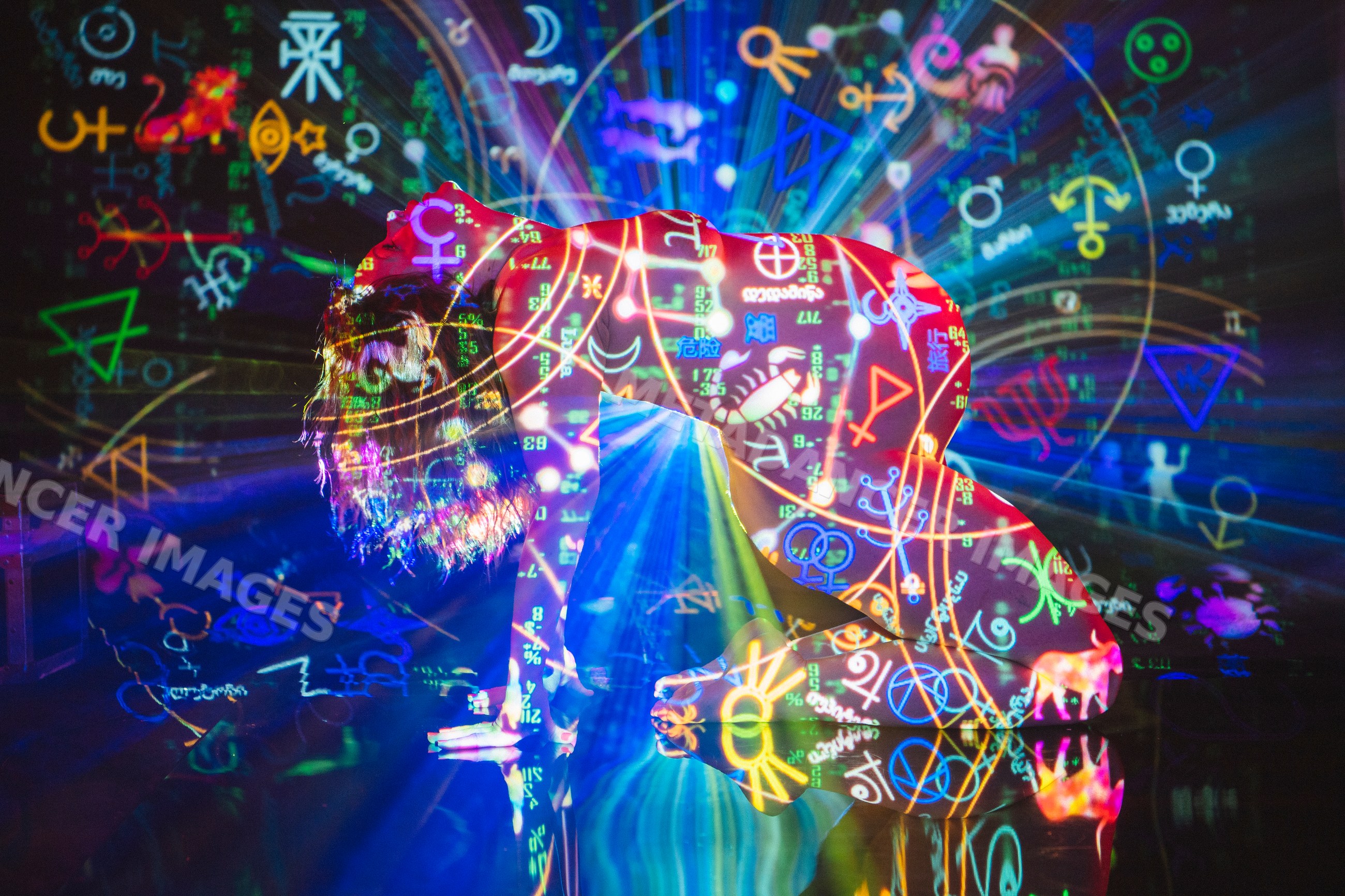 White person kneeling with colorful astrology symbol projections