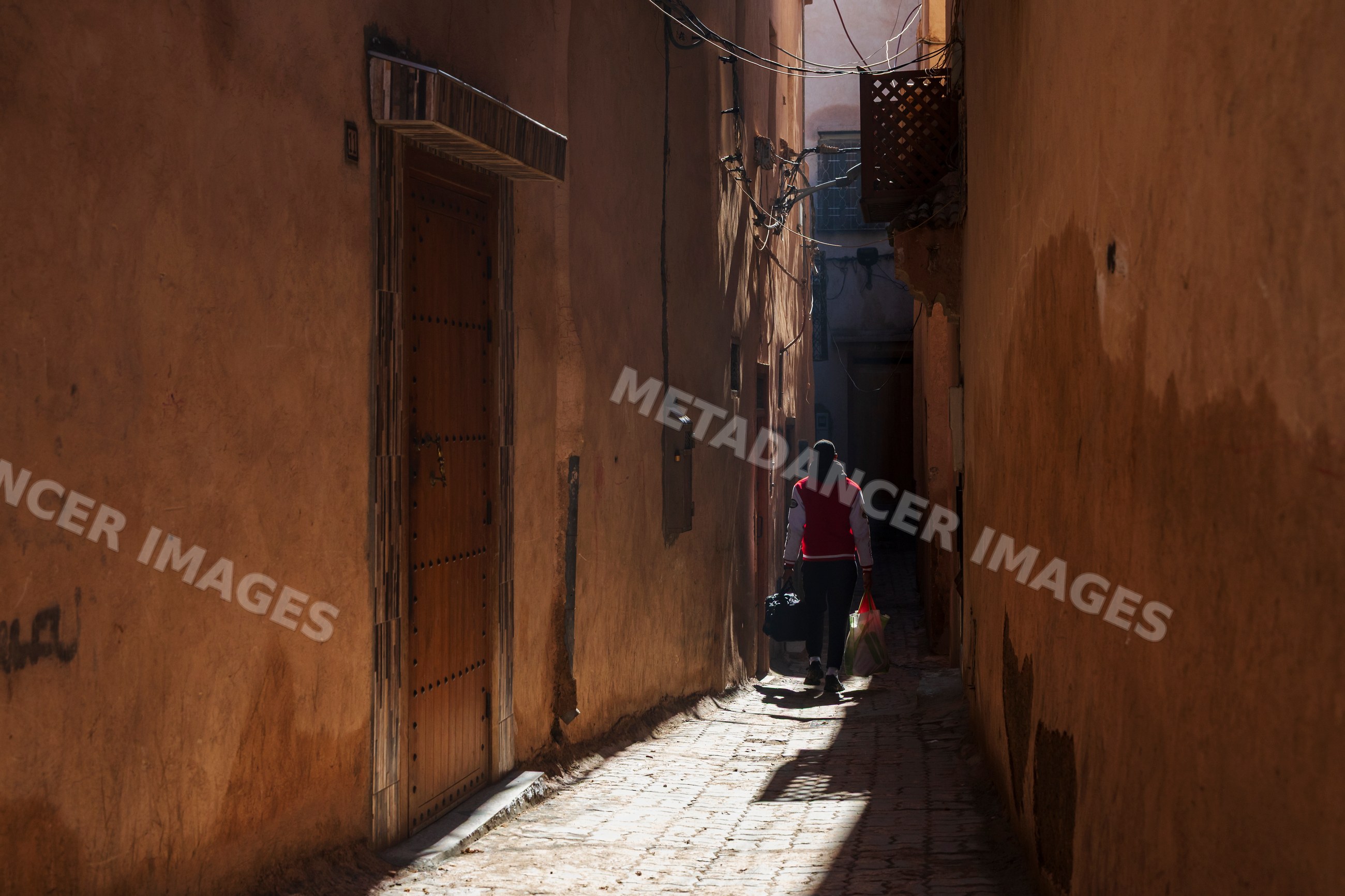 Man walking in narrow alleyway carrying grocery bags