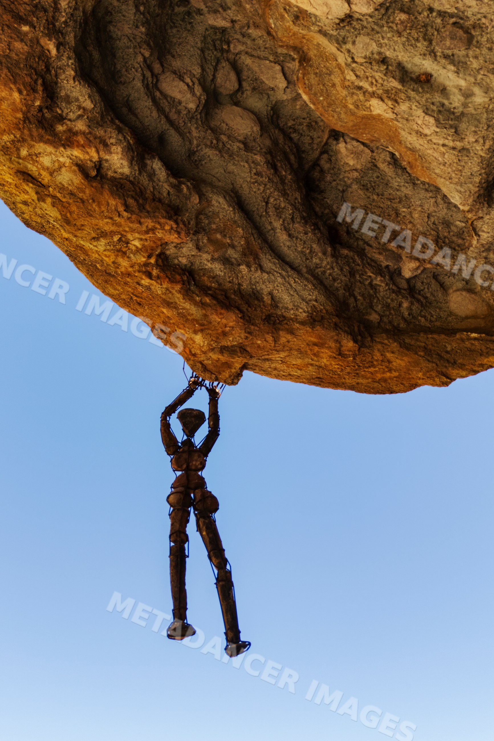 Rock man wire sculpture hanging from boulder, Namibia