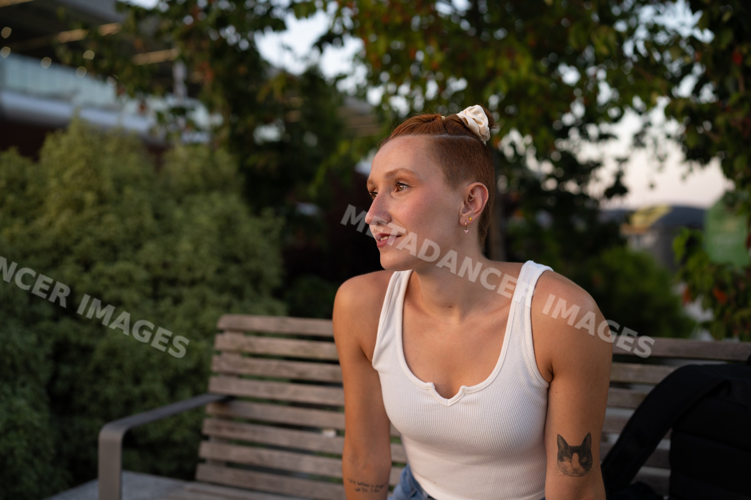 A young white woman sits on a wooden bench outdoors in Santiago