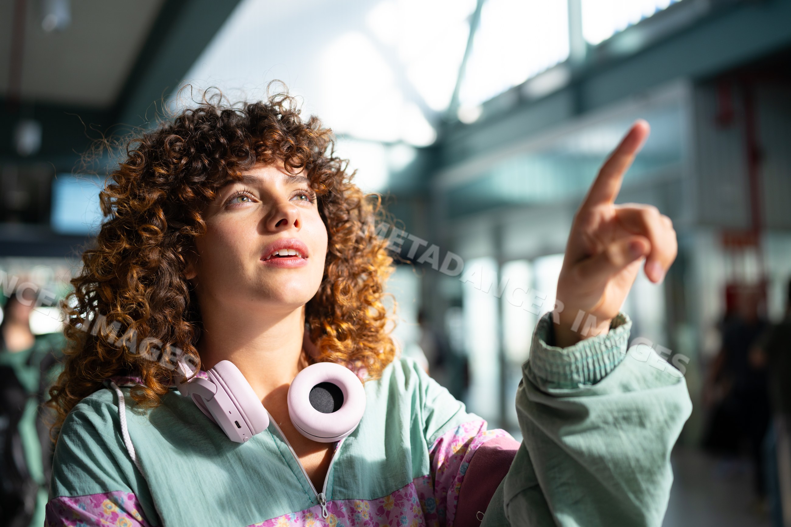 White woman with curly hair pointing inside modern indoor space