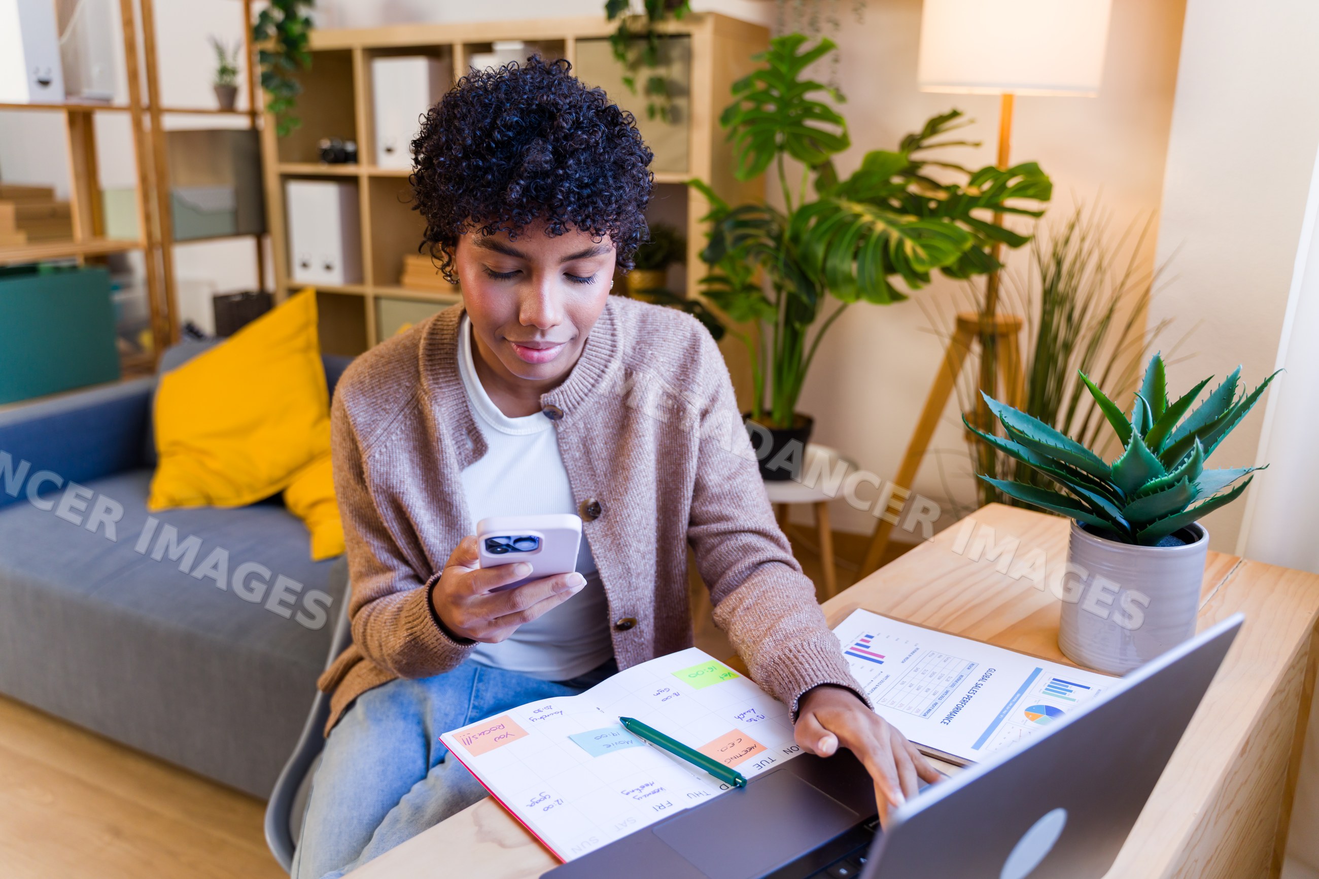 African American woman working remotely with smartphone and laptop