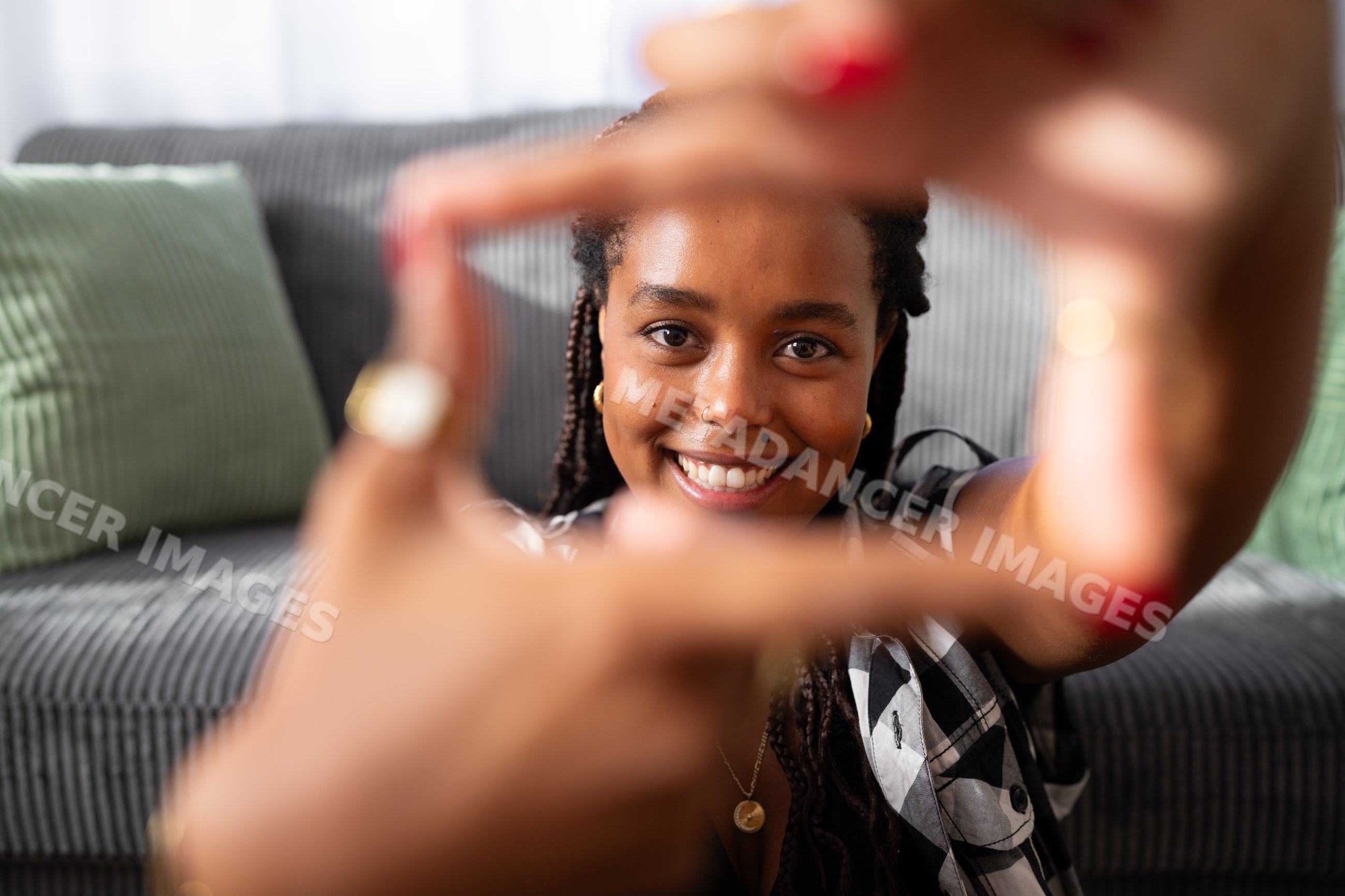 A young African American woman smiles framing her face with her hands