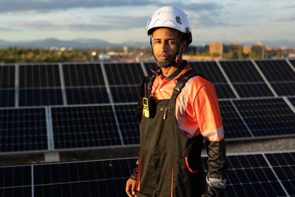 Worker inspecting solar panels on urban rooftop in Madrid, Spain