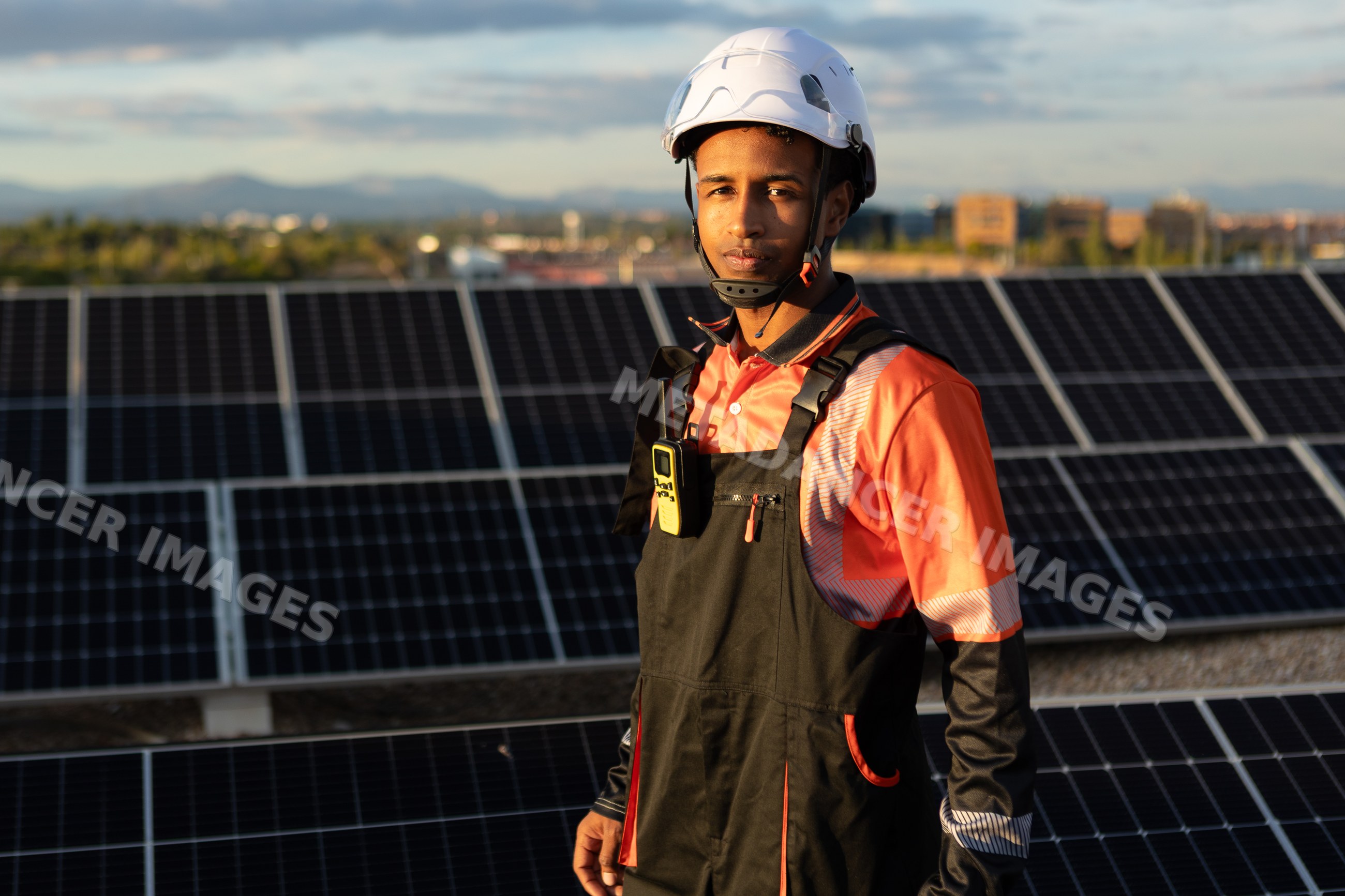 Worker inspecting solar panels on urban rooftop in Madrid, Spain