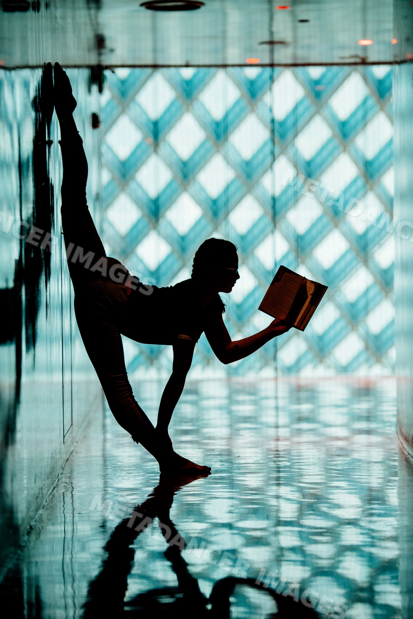 A person reads a book while doing yoga stretching