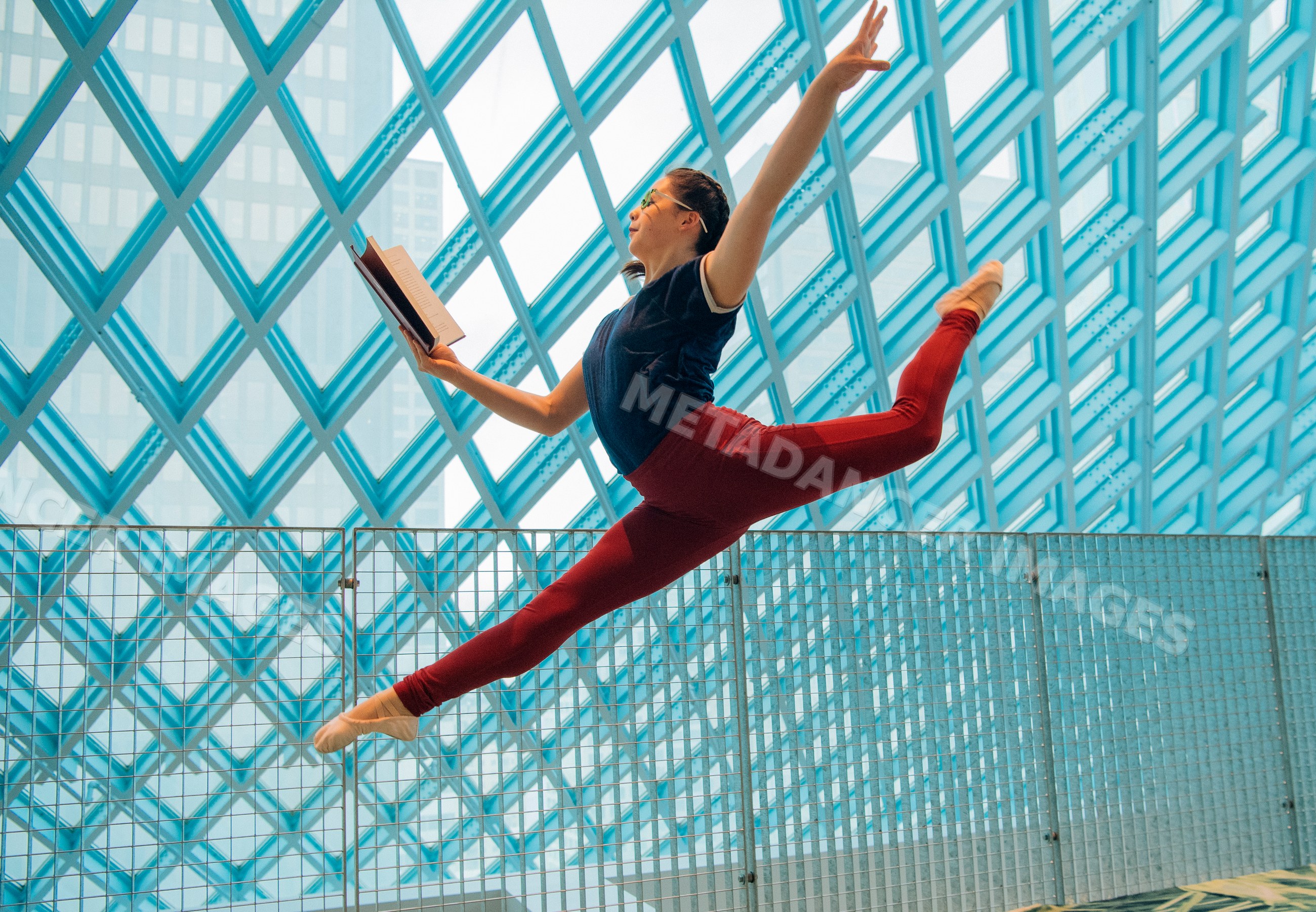 A female dancer leaps through the Seattle public library while reading