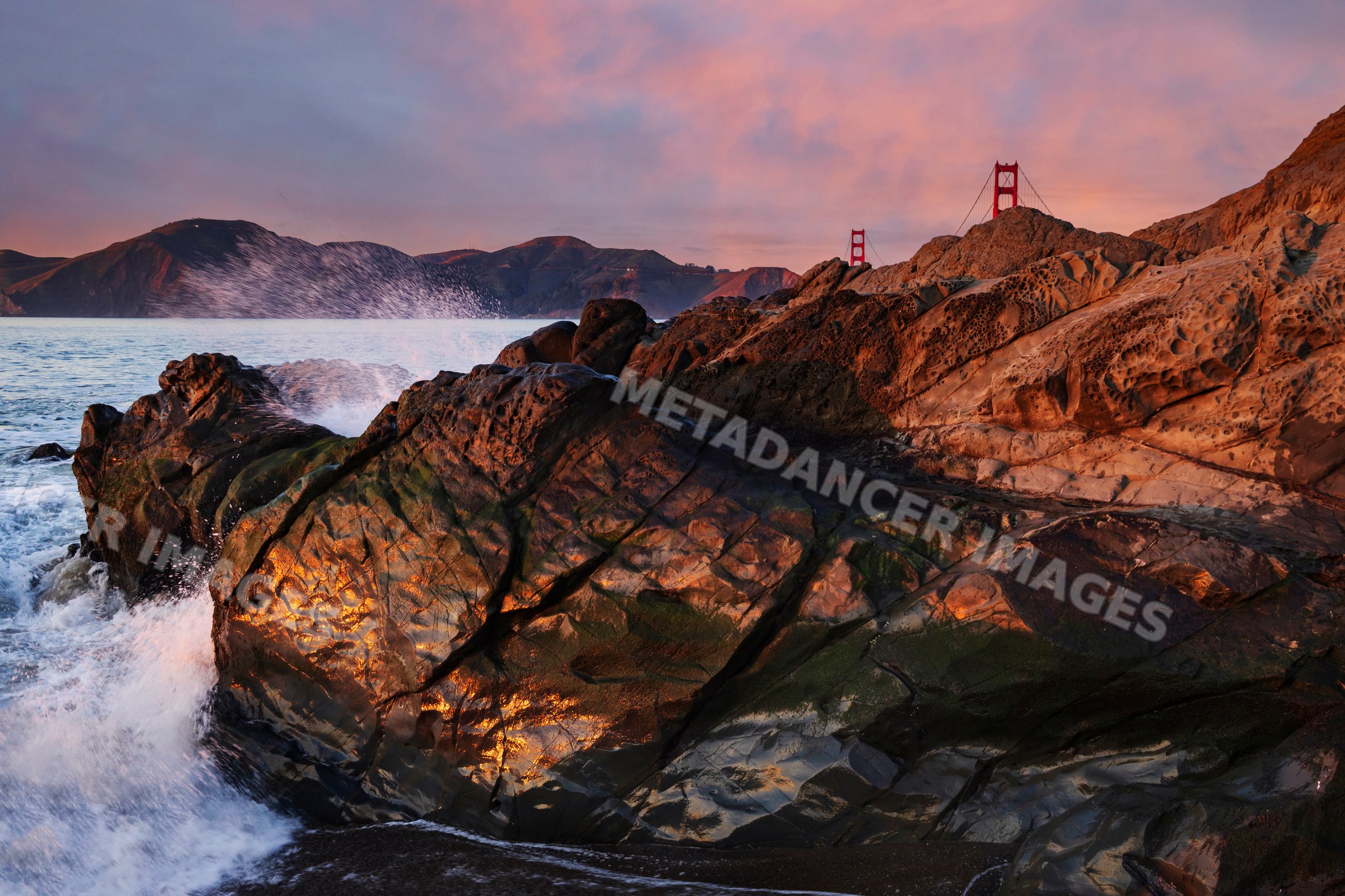 Rocks by ocean shore with golden gate bridge