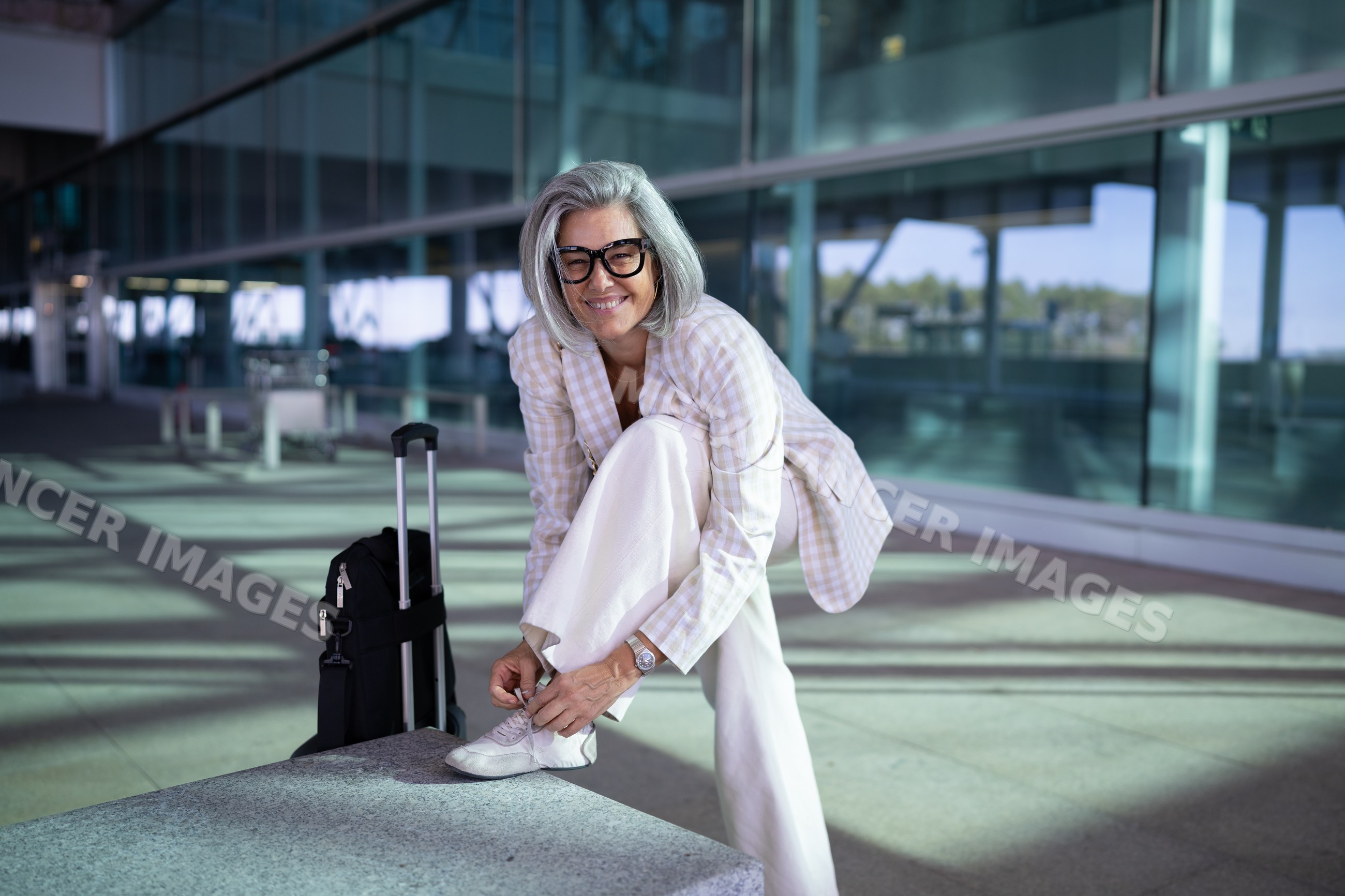 Businesswoman tying sneaker outside modern airport in Madrid, Spain