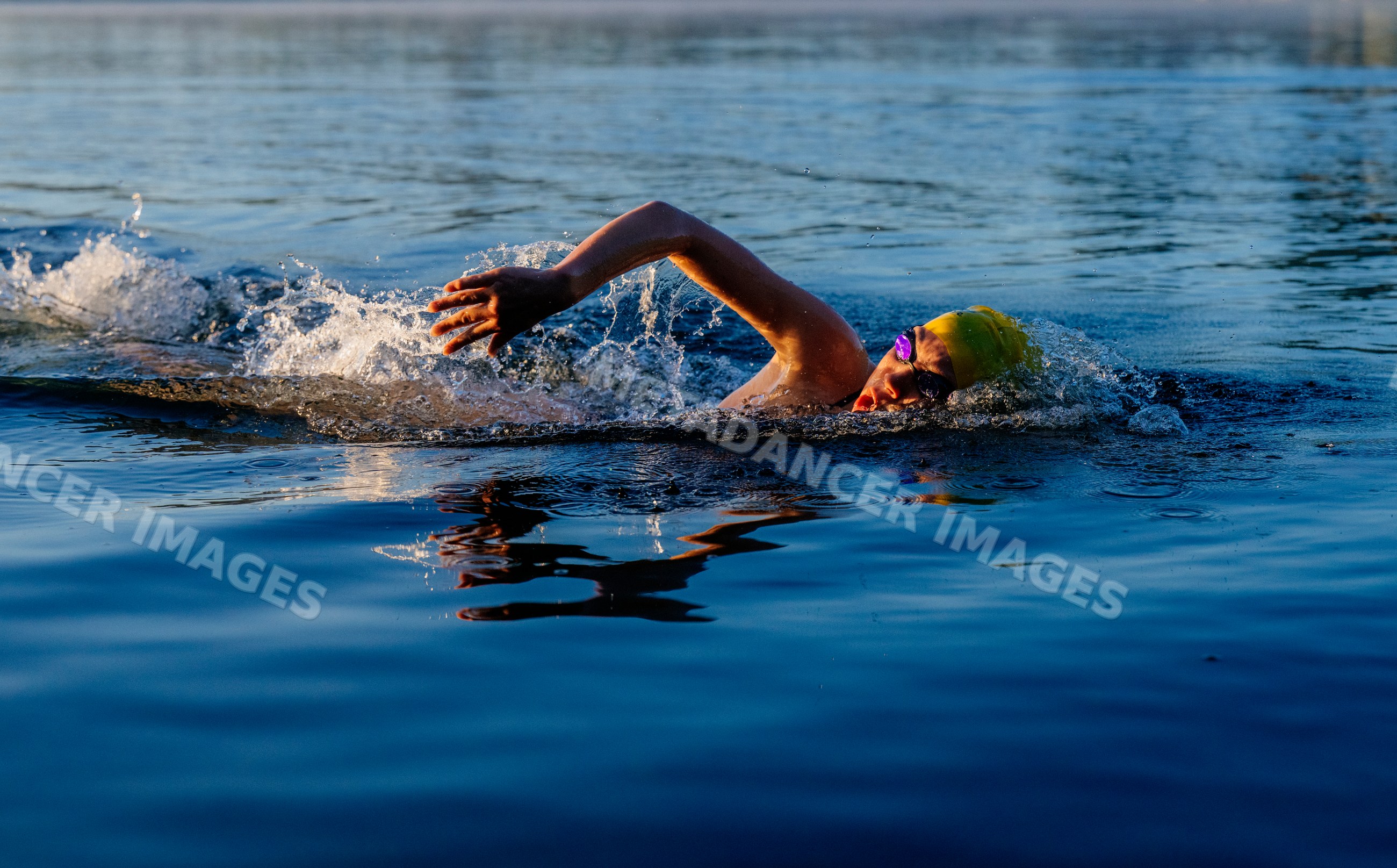White swimmer performing freestyle stroke in open water lake